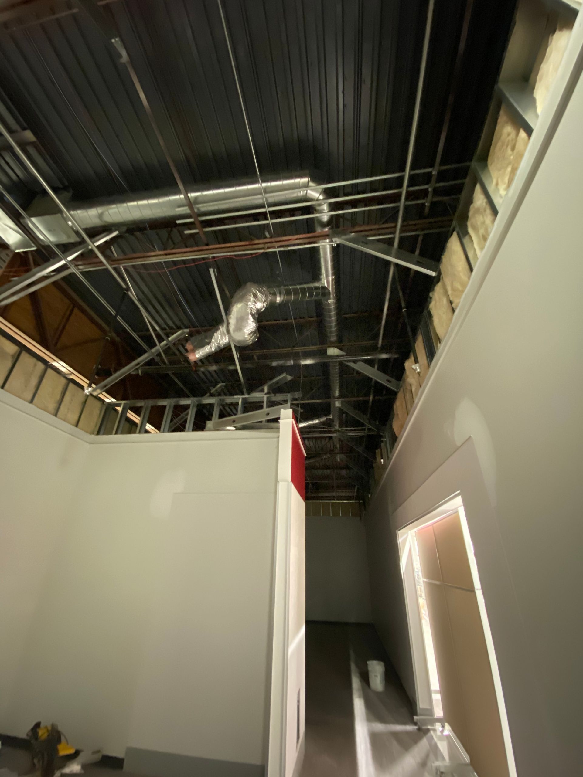 Interior view of construction, unfinished ceiling with metal beams, ducts, and partially built walls.