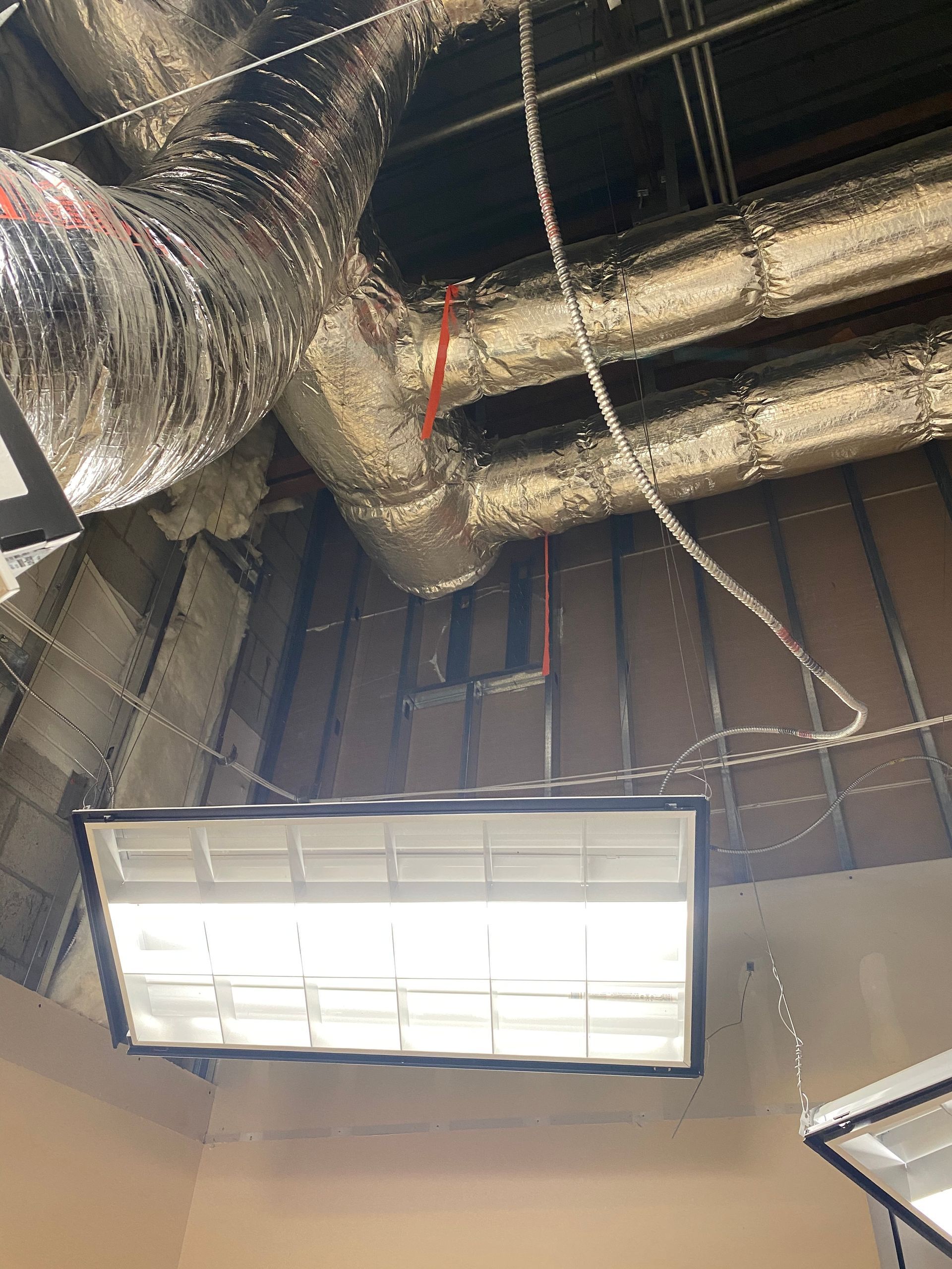 Fluorescent lights under ductwork in a commercial setting.