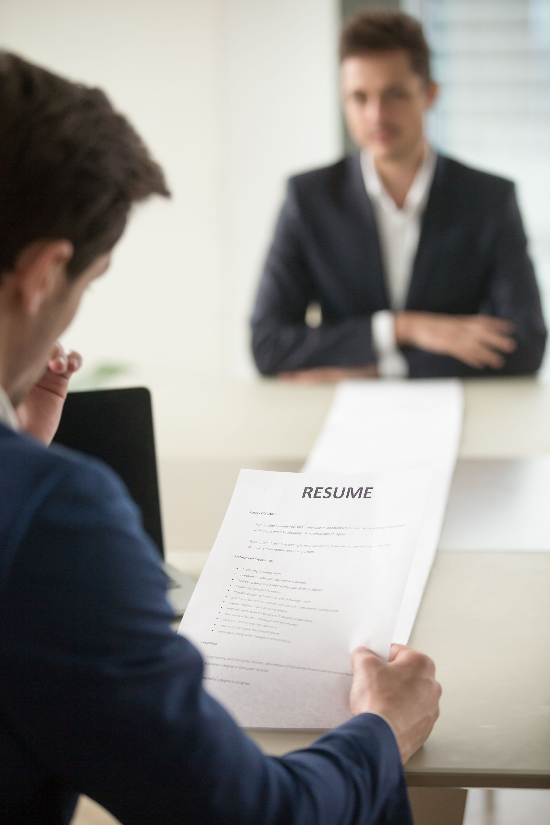 Employer reviewing a job applicant’s resume during an interview, highlighting the impact of background checks.