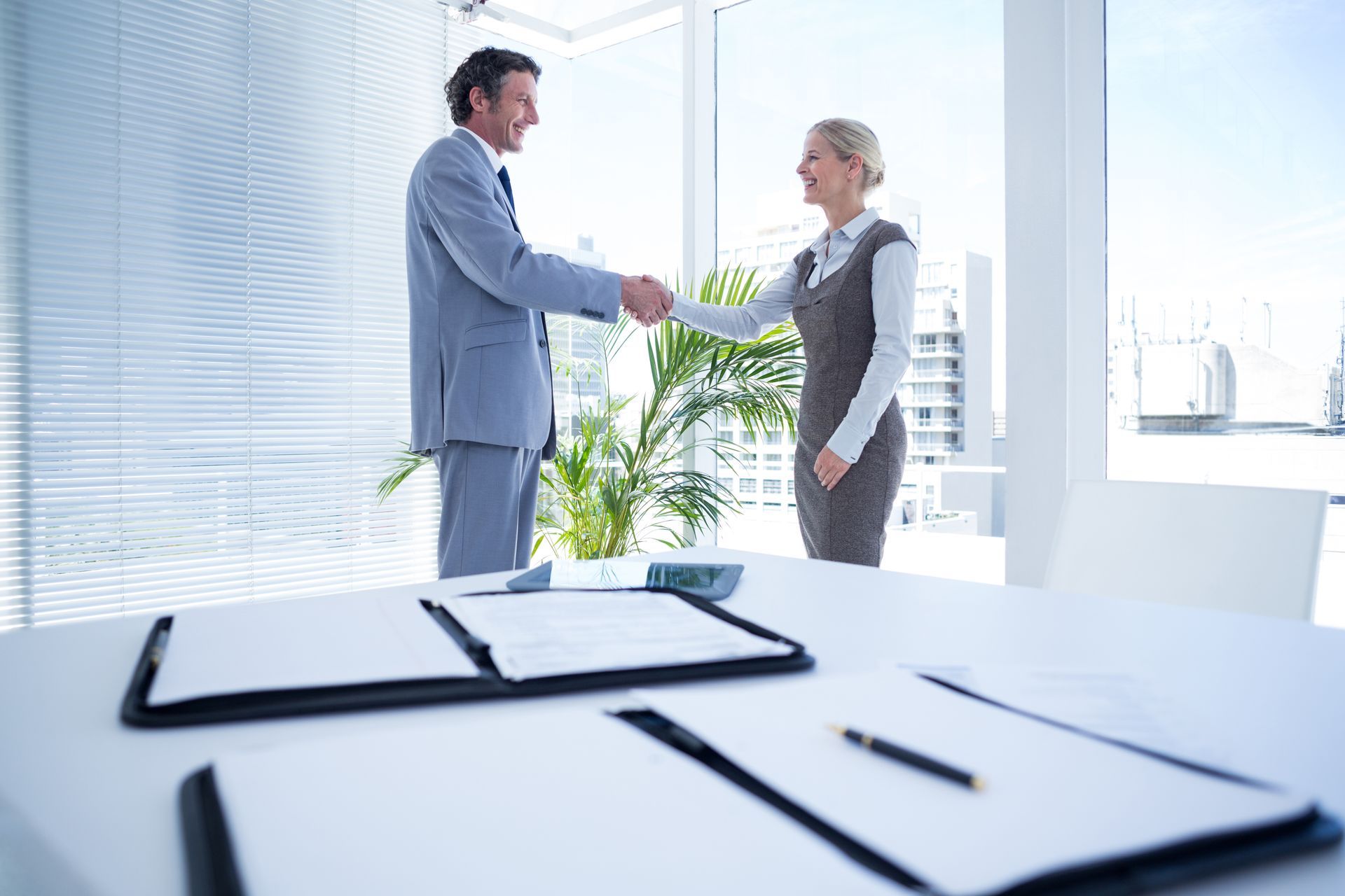 Smiling landlord and legal representative shaking hands in a modern office, celebrating a successful resolution.