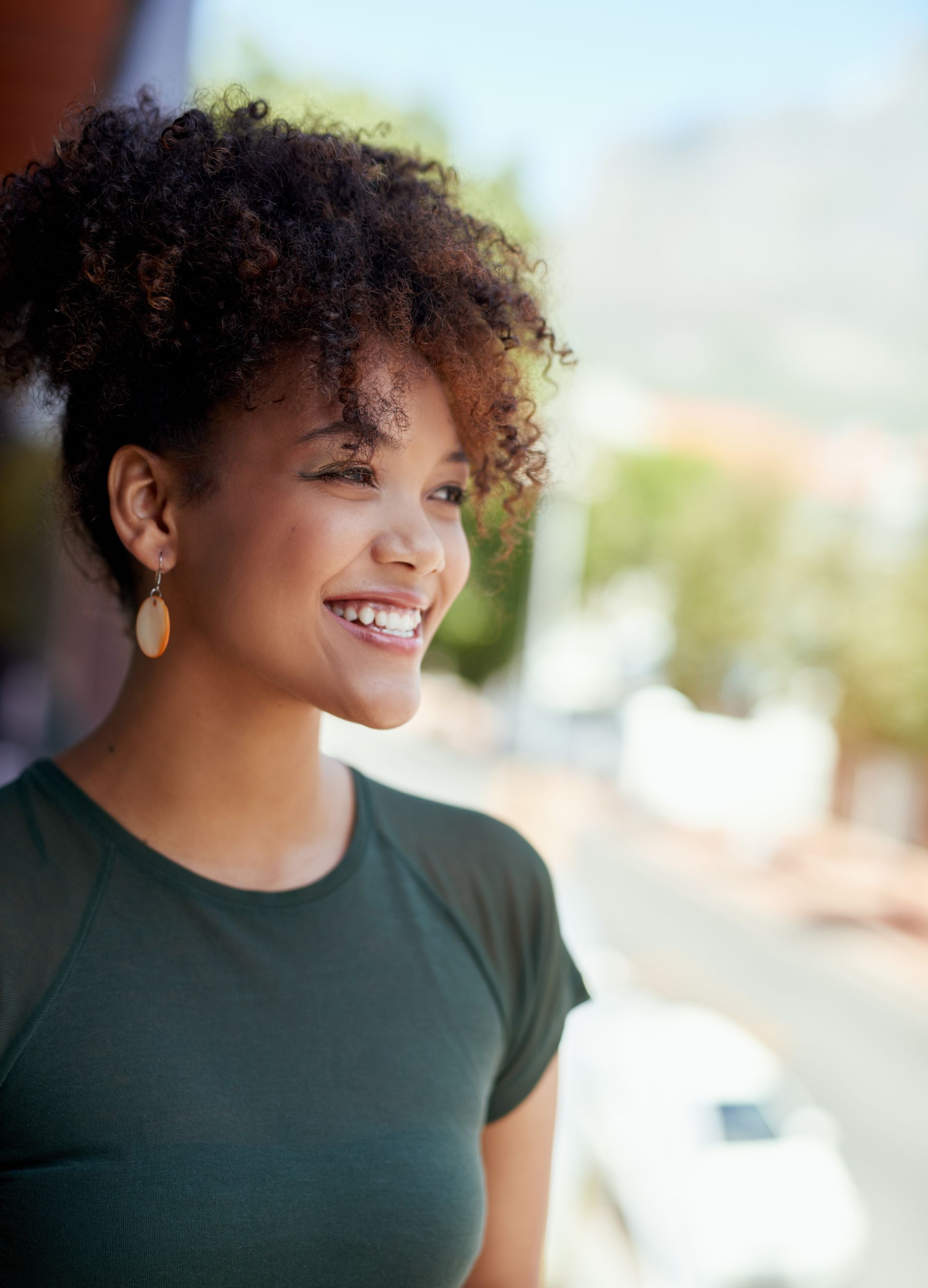 Smiling woman looking into the distance from a sunny balcony, representing a fresh start after receiving a criminal record suspension.