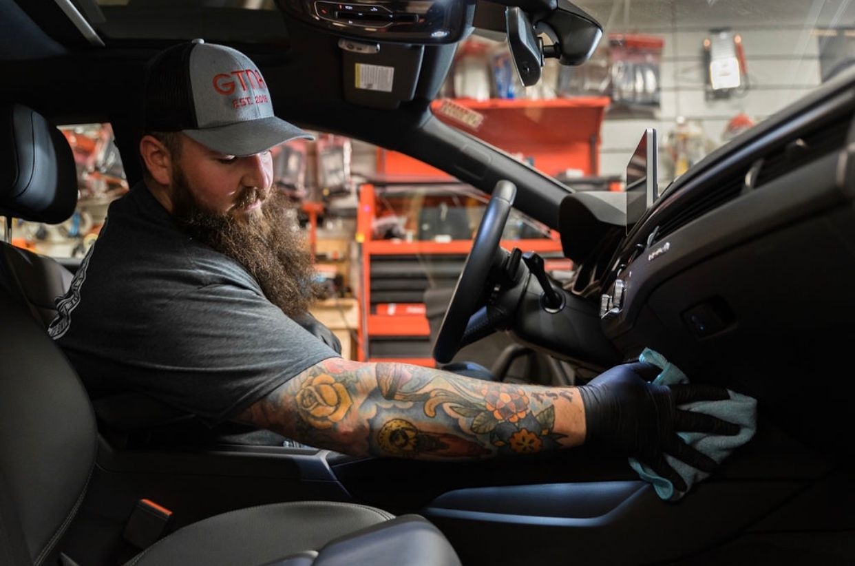 Car interior with a brown leather steering wheel, dashboard, and seats.