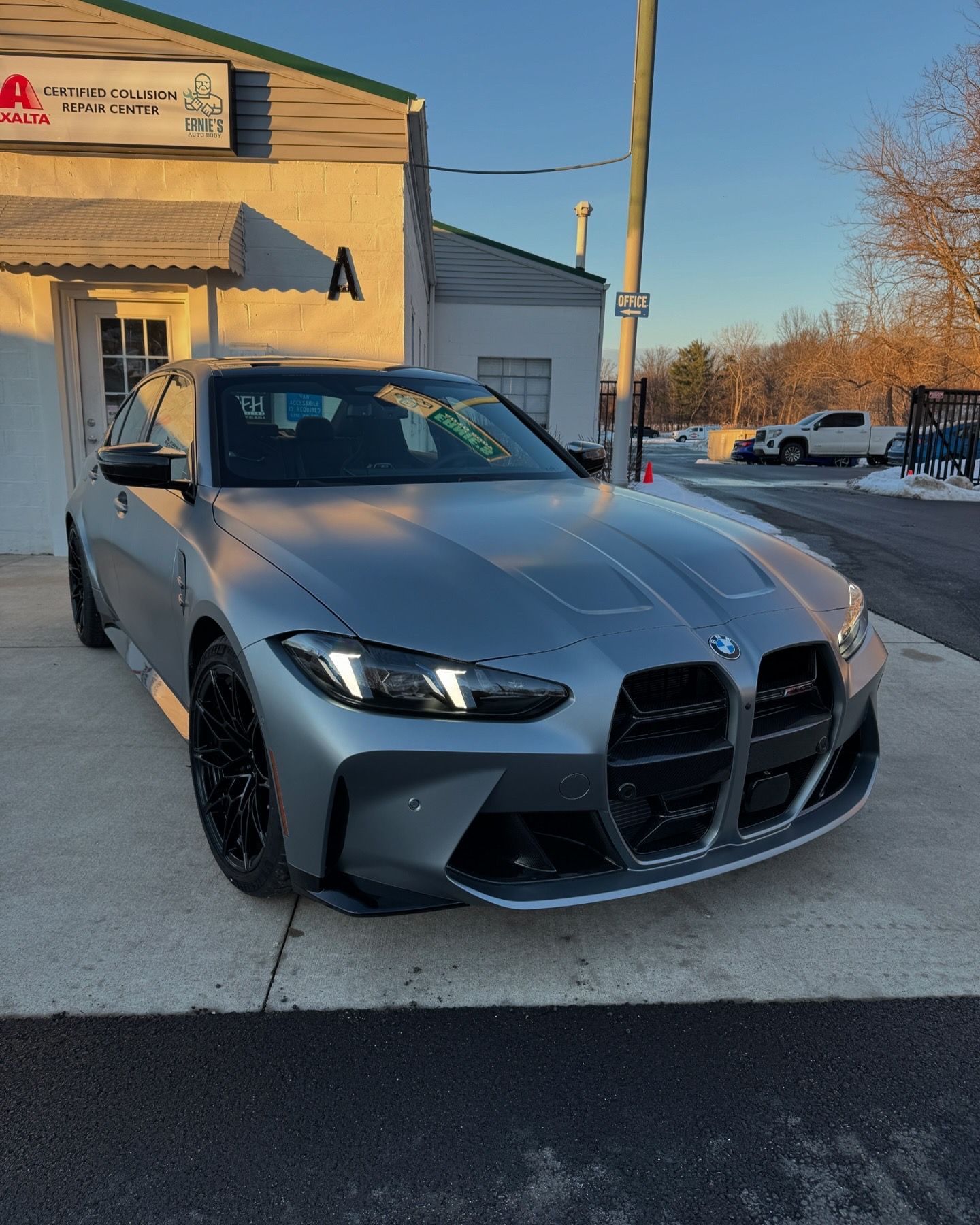 Silver BMW M4 coupe parked in front of a building with the letter 