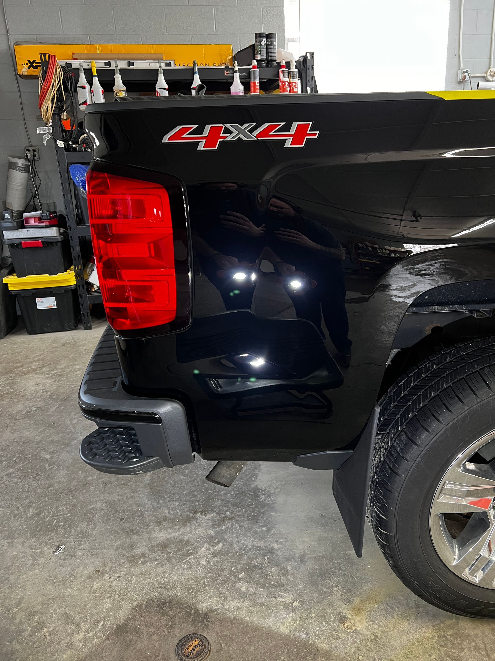 Black truck bed with 4x4 emblem, red taillight, and rear tire.
