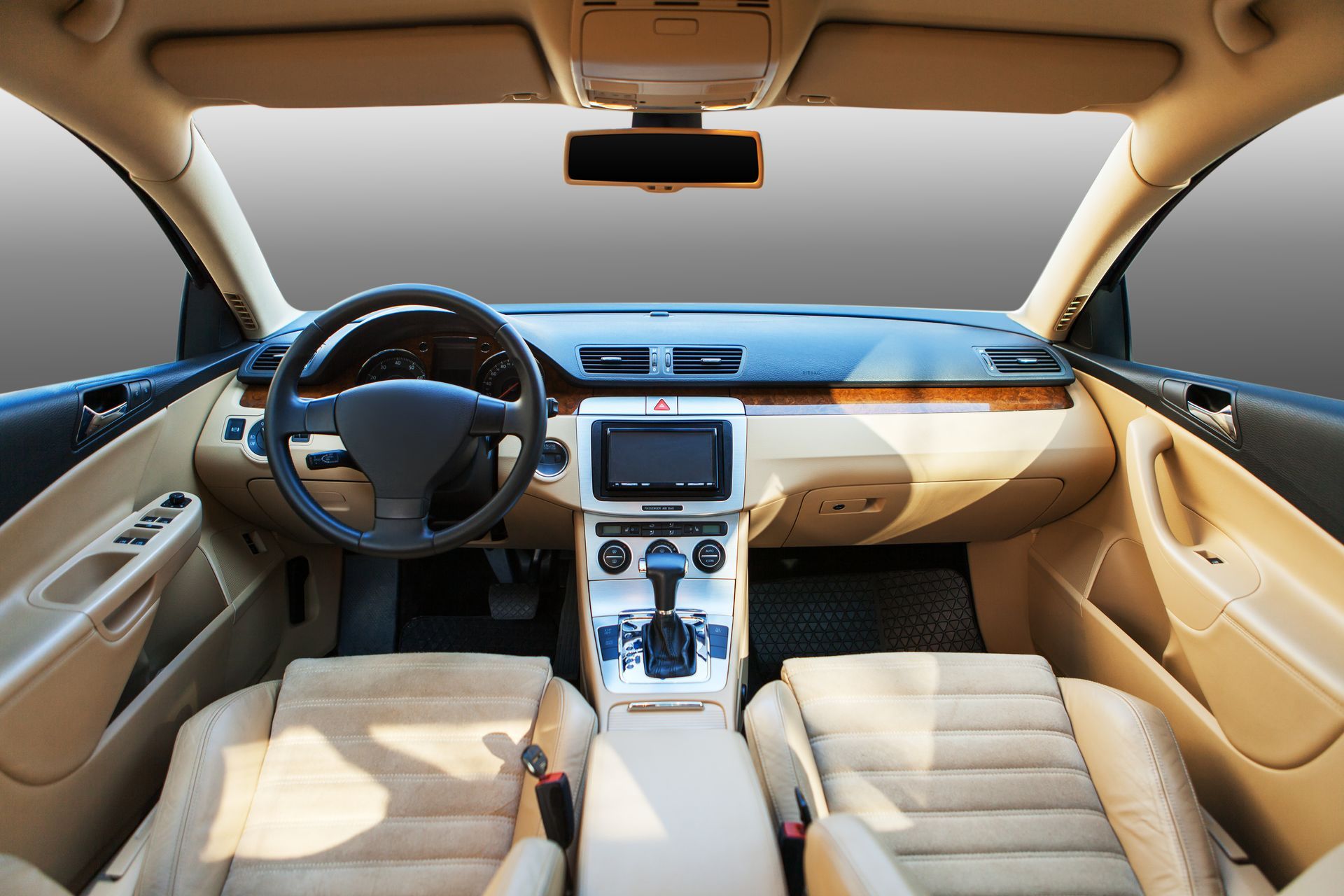 Interior view of a beige car. Dashboard, steering wheel, seats, and console are visible.
