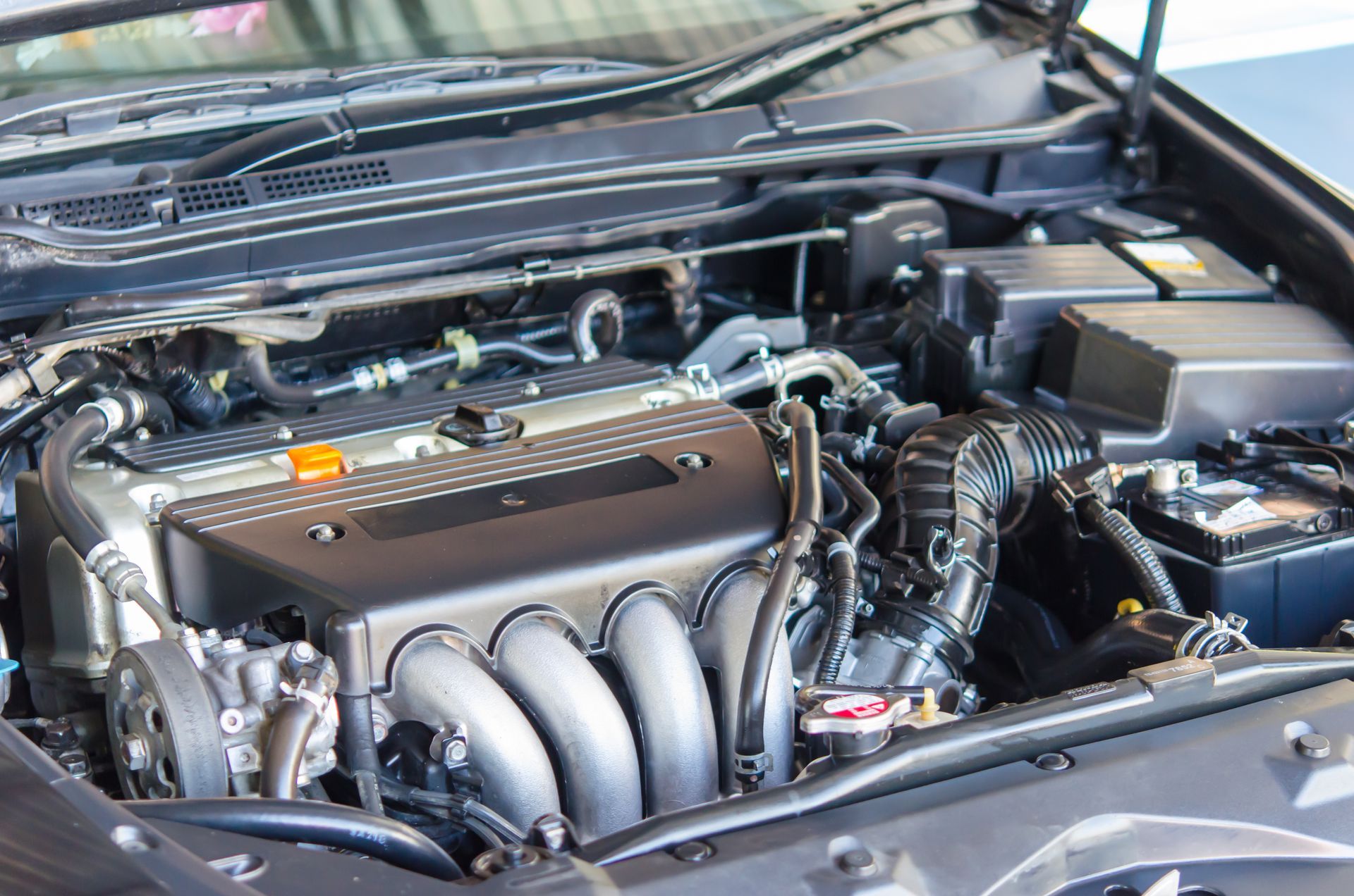 Car engine bay, black and silver components, viewed from above, detailed view.