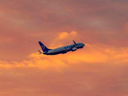 Airplane flying across an orange sunset sky