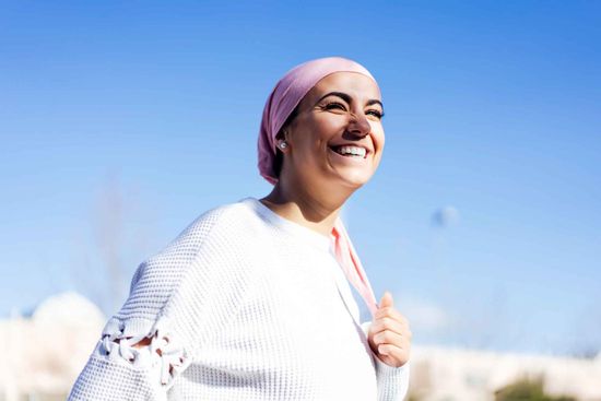 A Woman Wearing A Pink Head Scarf And A White Sweater Is Smiling – Independence, MO - Mary Hargrave