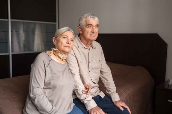 An Elderly Couple Is Sitting On A Couch In A Bedroom – Independence, MO - Mary Hargrave