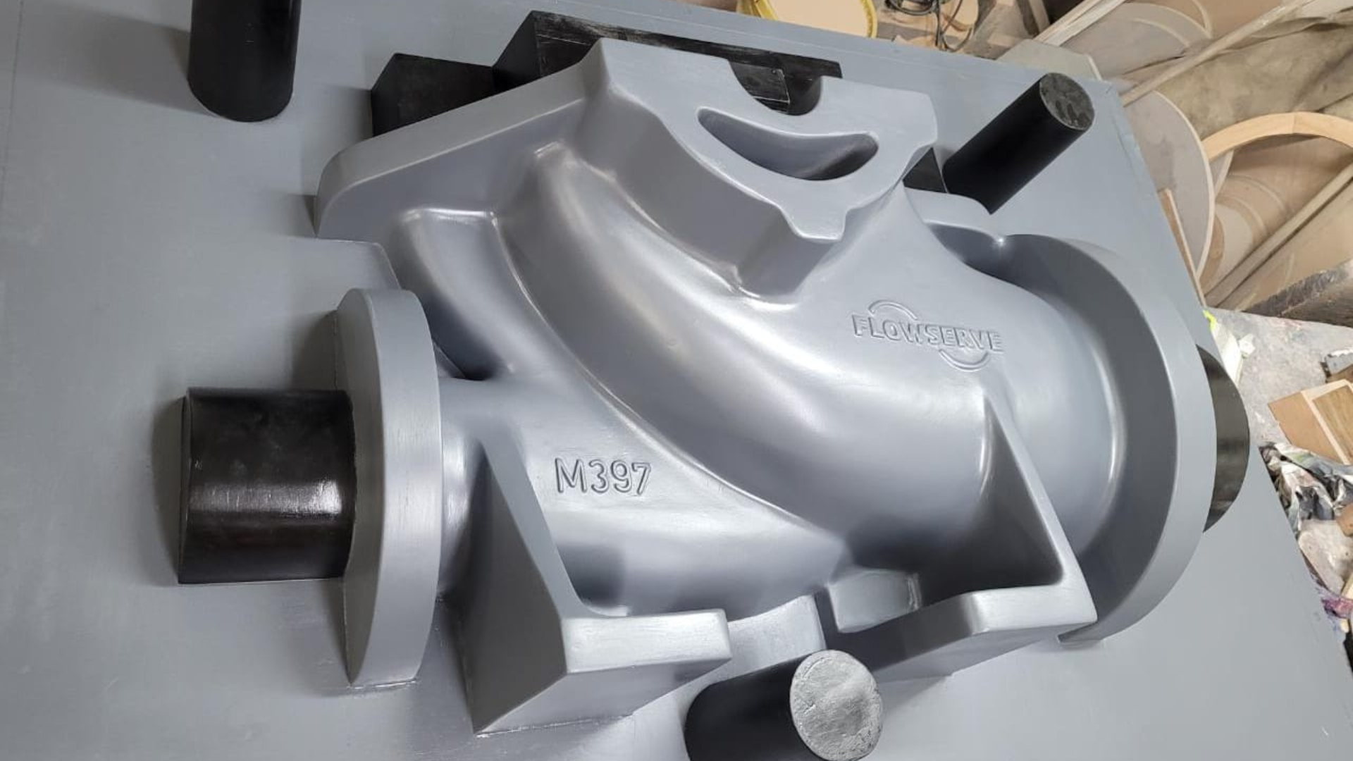 Molde de fundición de metal gris de una pieza industrial con accesorios cilíndricos.