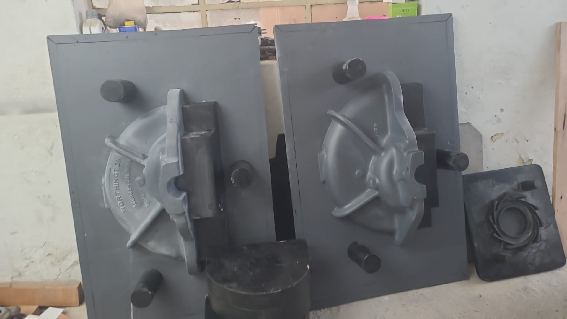 Dos moldes grises, potencialmente para fundición, con componentes adjuntos.