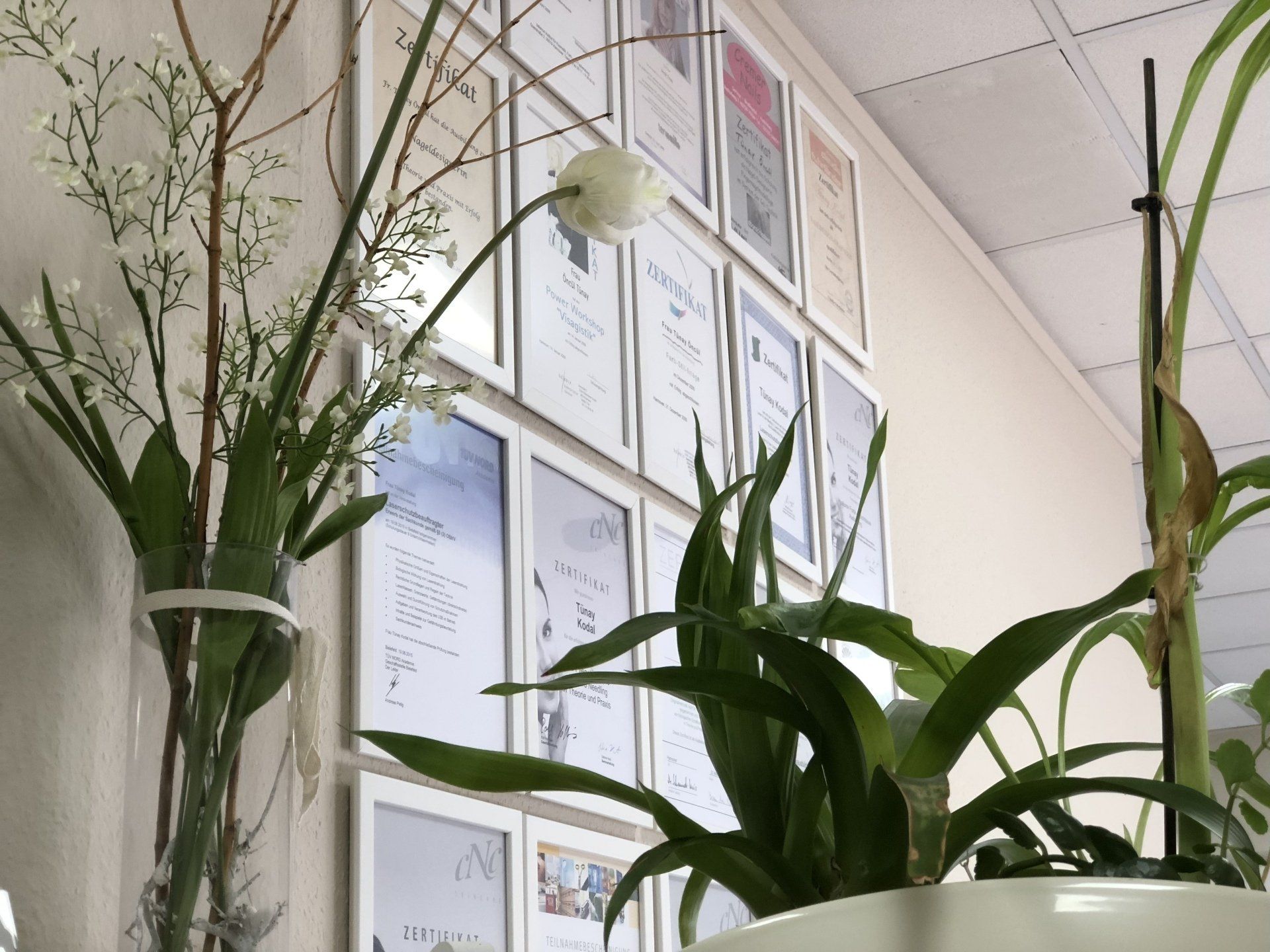 Eine Vase mit Blumen steht vor einer Wand mit gerahmten Bildern