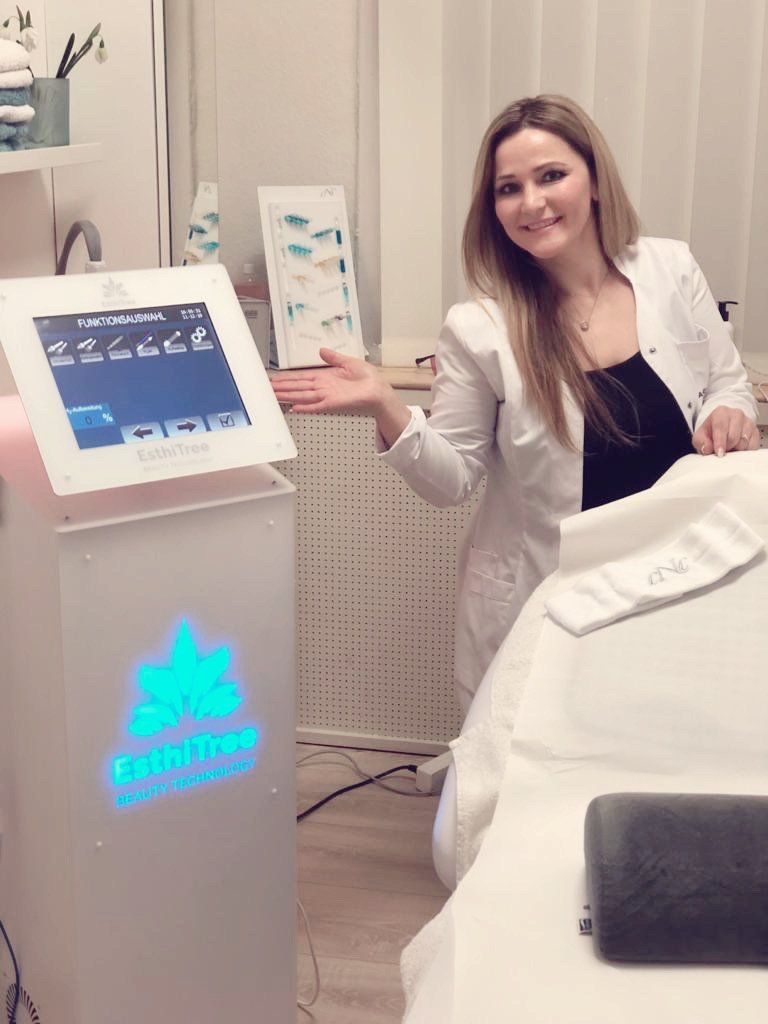 Eine Frau im Laborkittel steht vor einer Maschine.