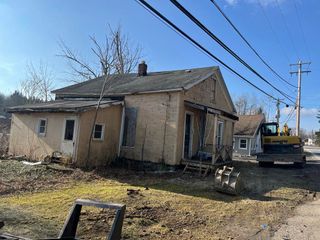 A dirt field with trees in the background and a house in the background.