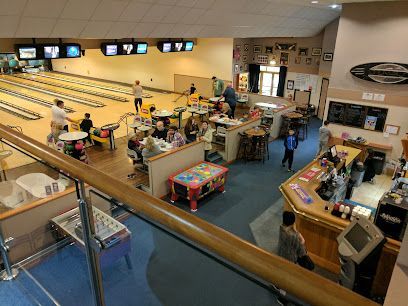 Bowling alley with several people, lanes, score screens, and a snack counter.
