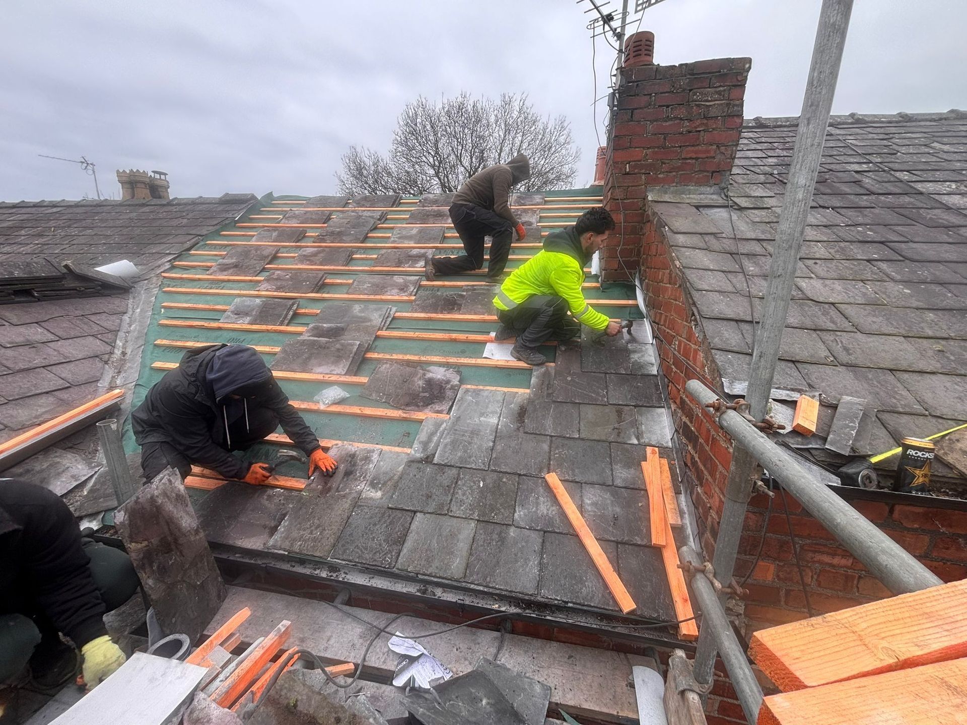 An aerial view of a residential area showing a house undergoing roof renovations, with scaffolding set up on the side.