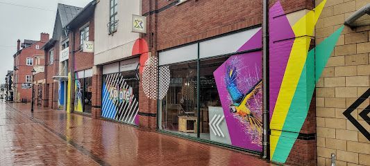 Rainy street with colorful mural-covered shopfronts and reflections on the wet pavement