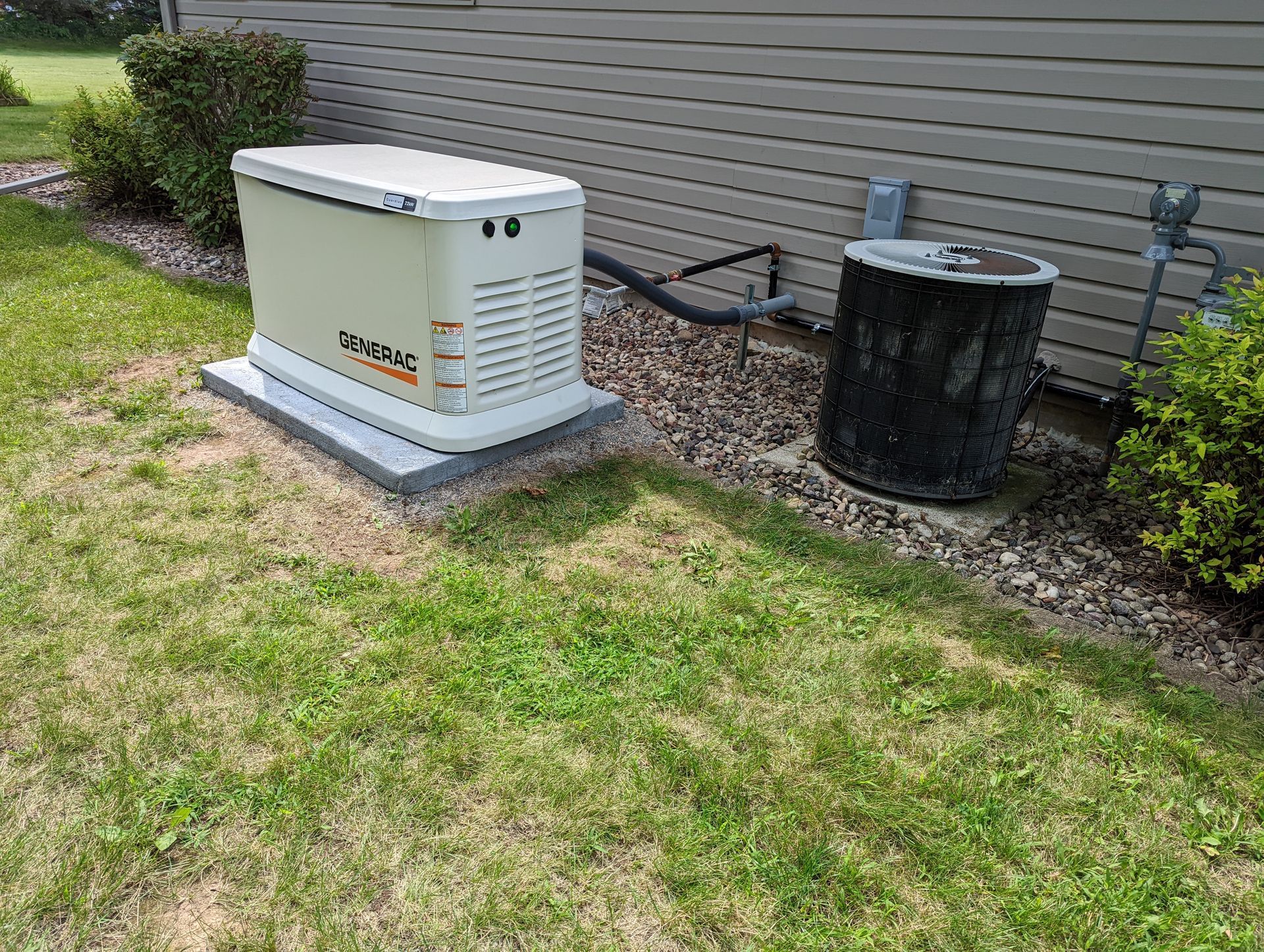 A generator is sitting in the grass next to a house.