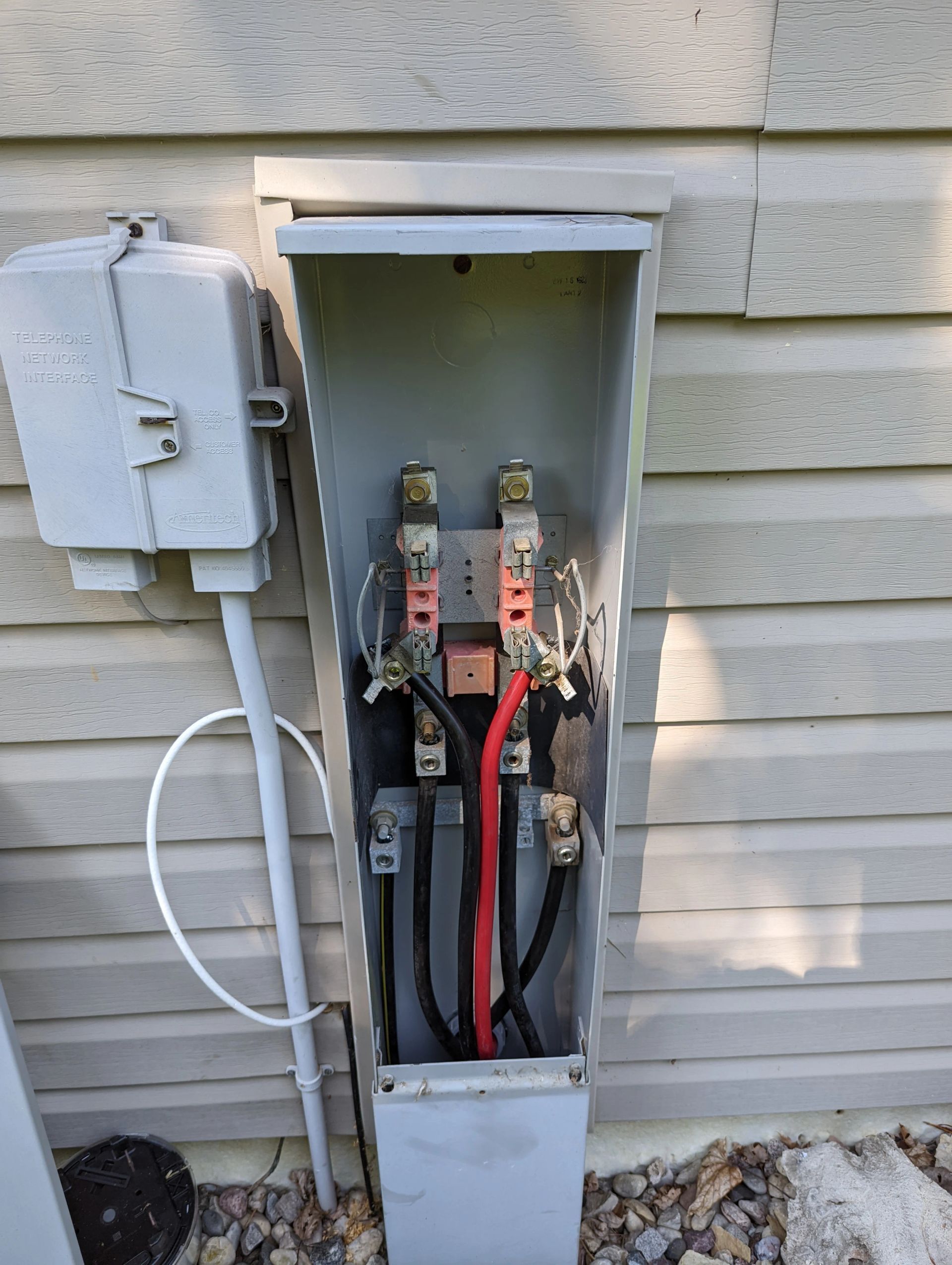 A electrical box is sitting on the side of a house.