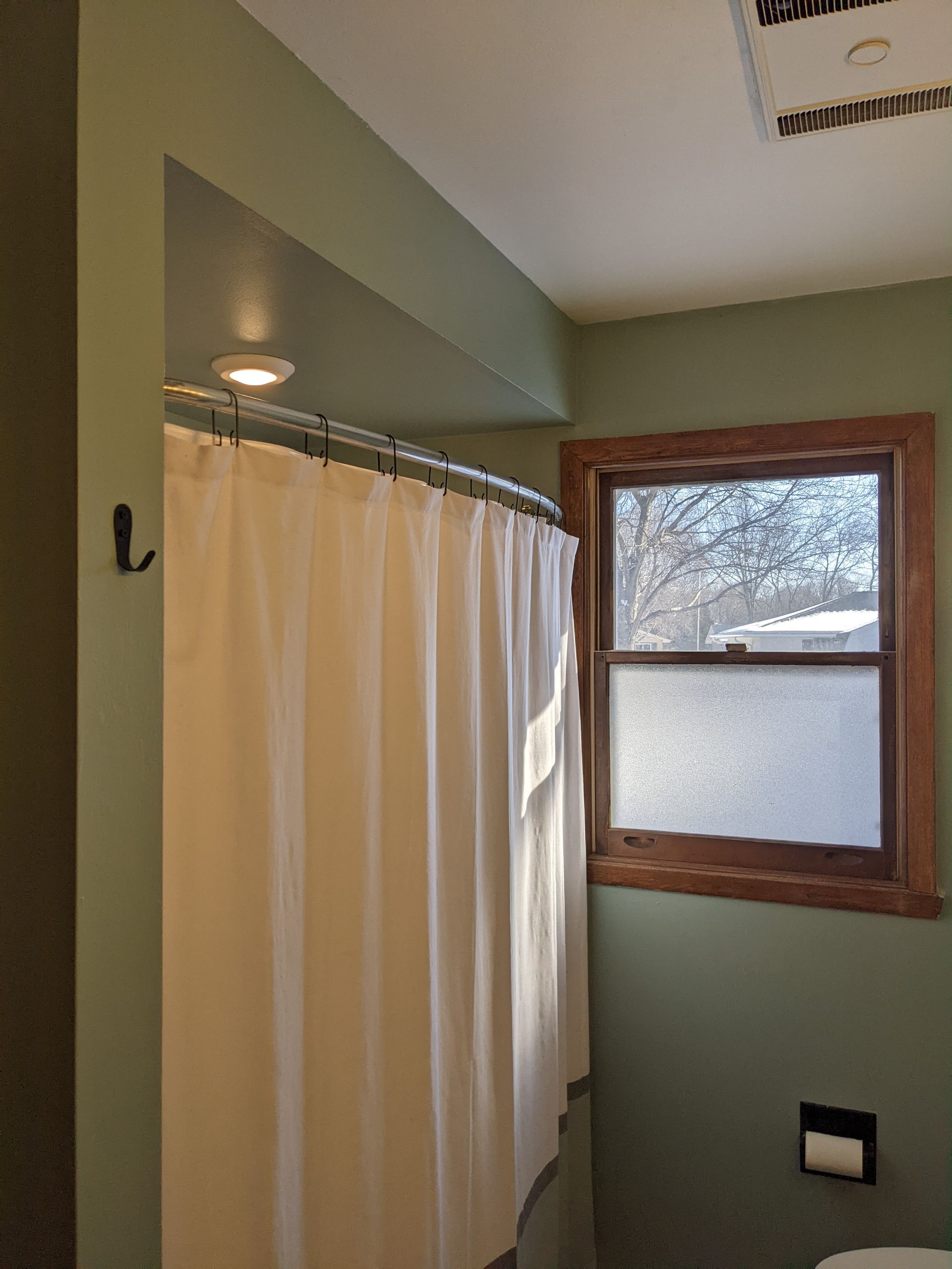 A bathroom with a shower curtain and a window