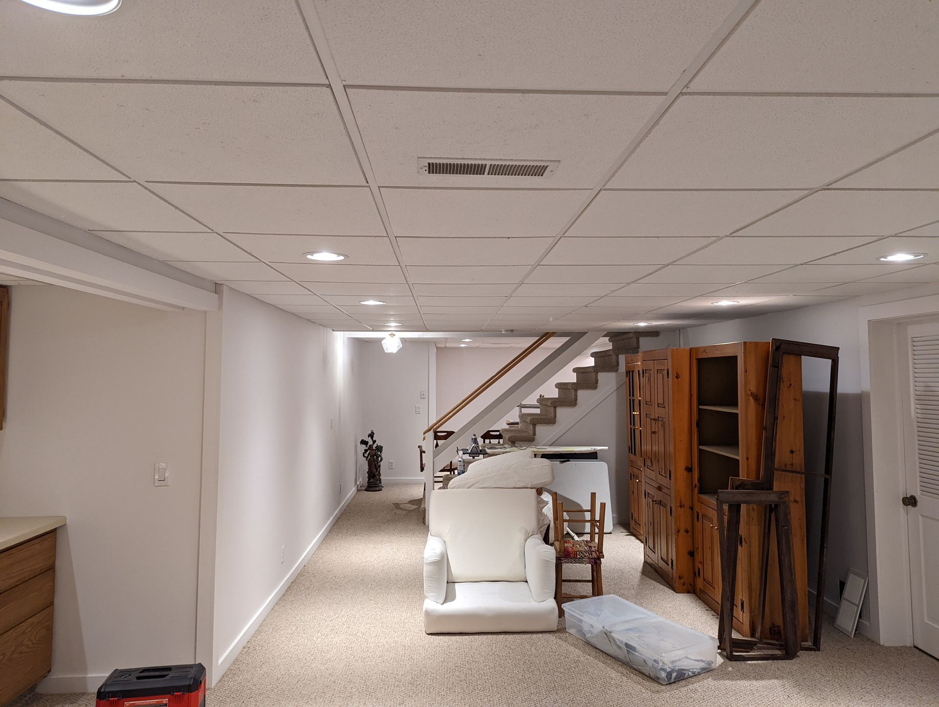 A living room in a basement with a chair and stairs.