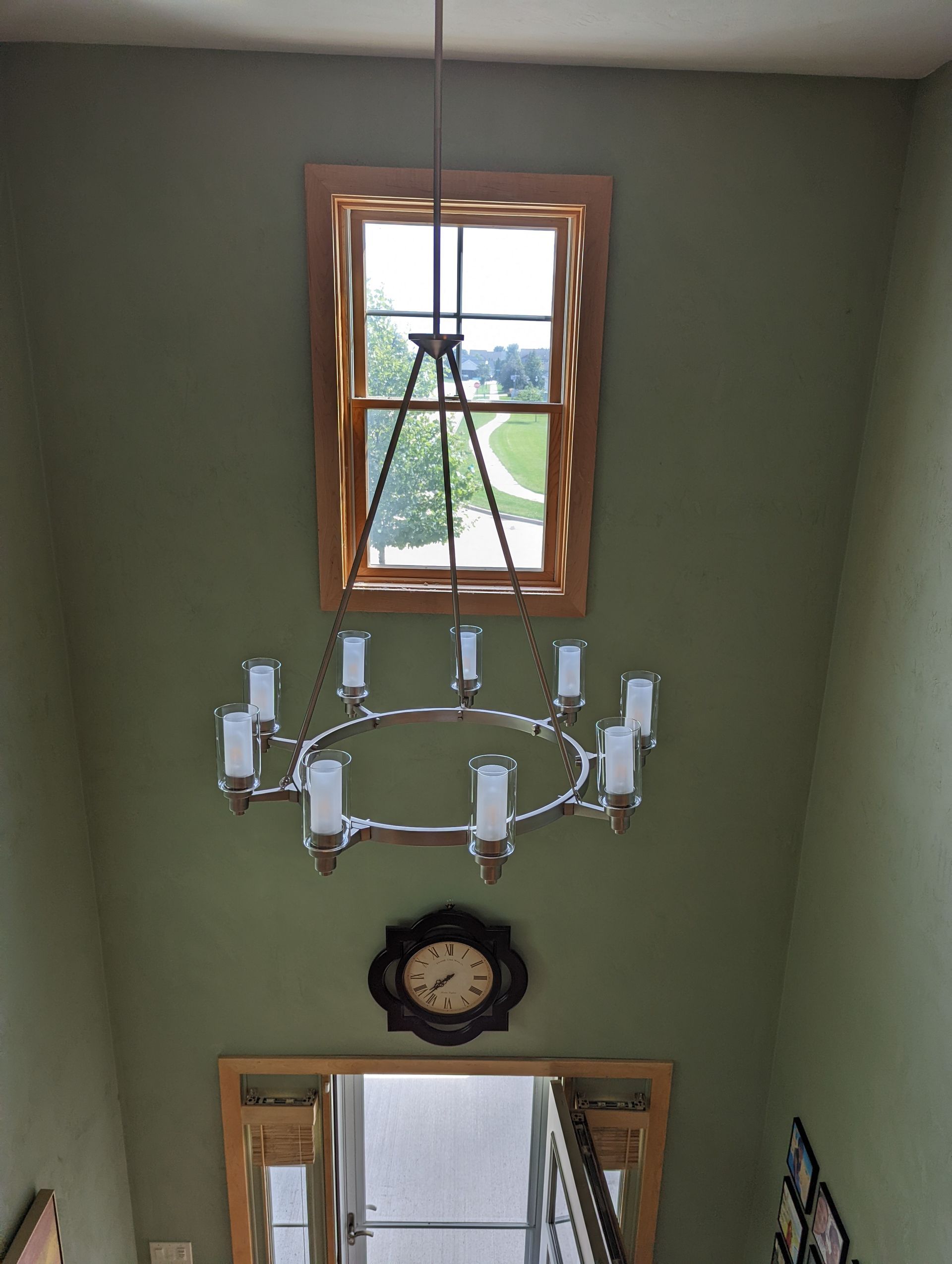 A staircase with a chandelier hanging from the ceiling and a clock on the wall.