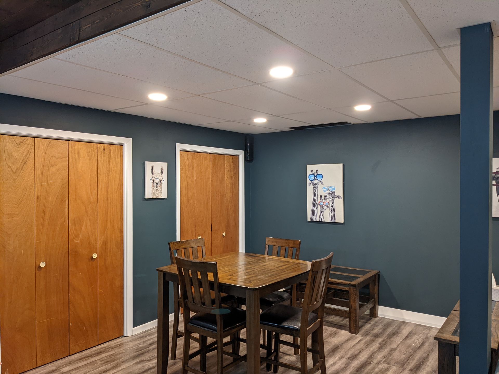 A dining room in a basement with a table and chairs.