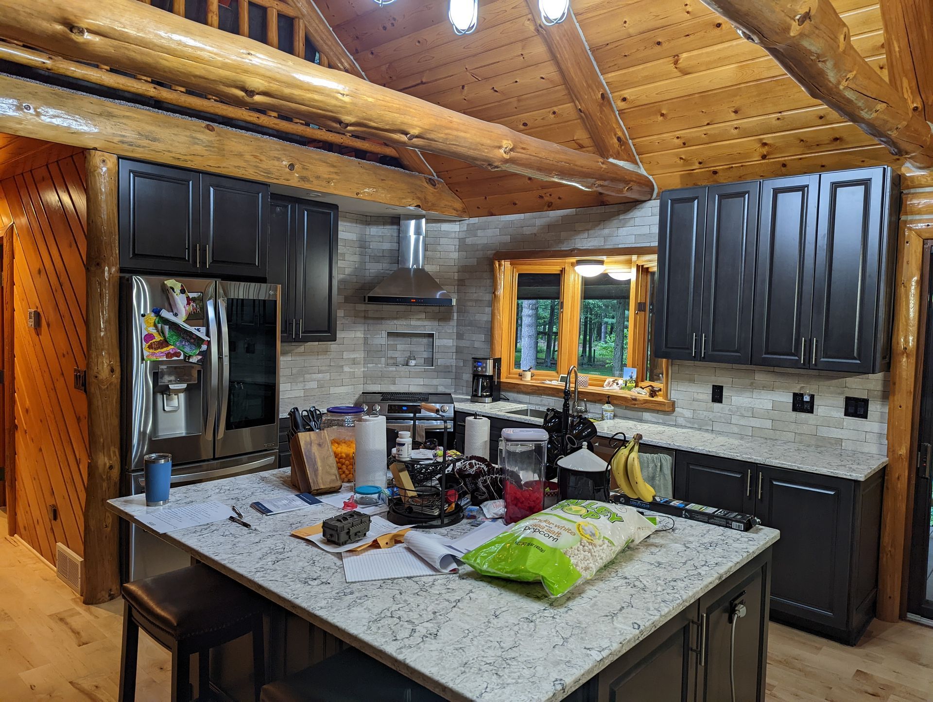 A kitchen in a log cabin with black cabinets and granite counter tops.