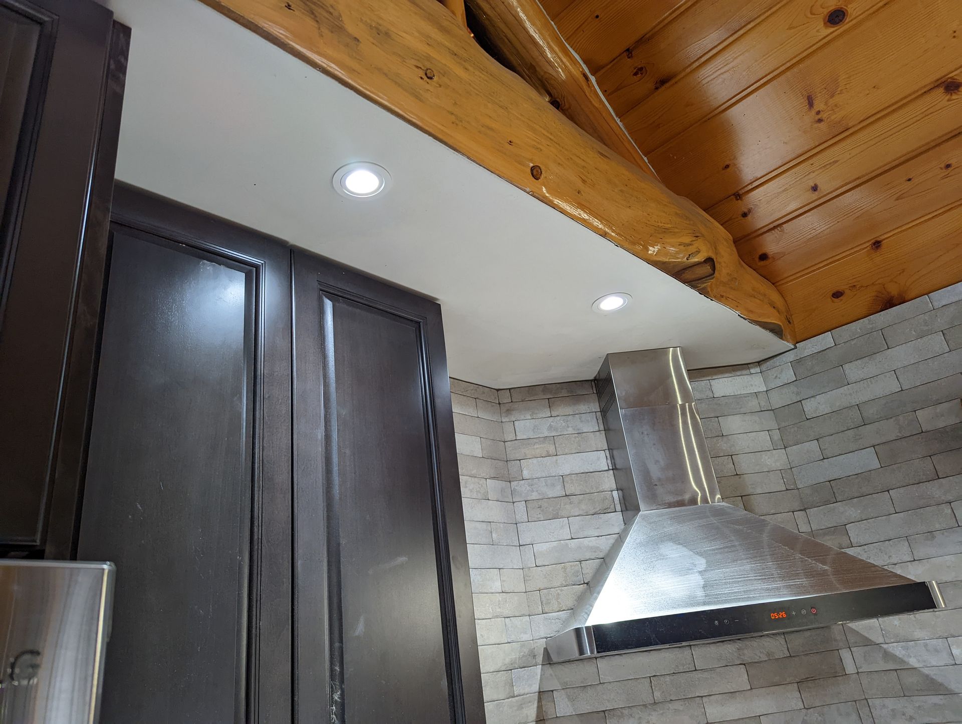 A kitchen with a wooden ceiling and a stainless steel hood