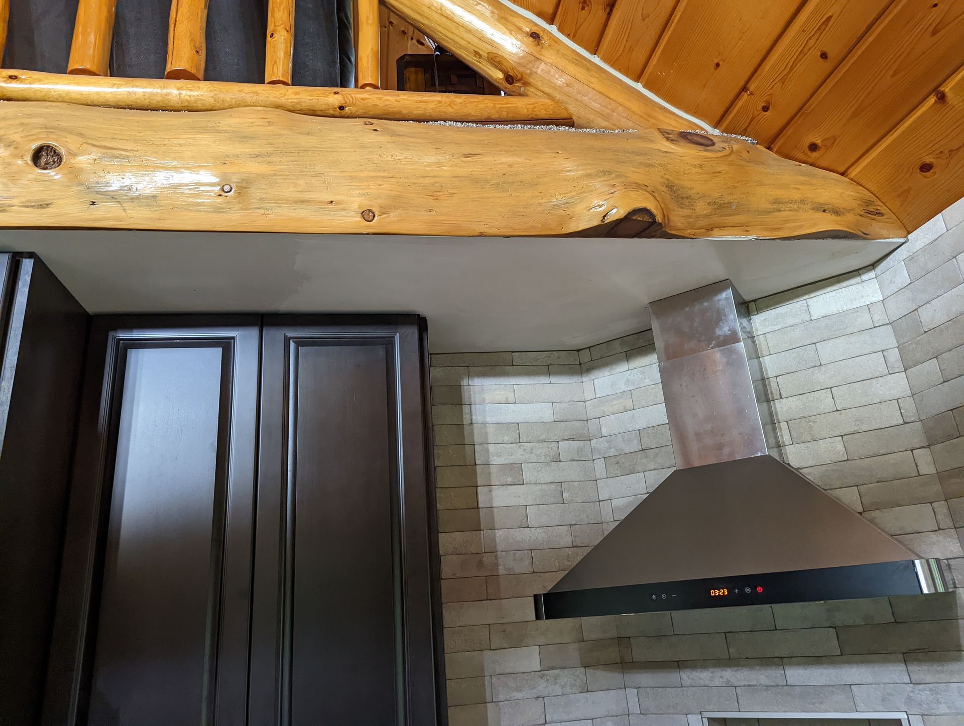 A kitchen with a wooden ceiling and a stainless steel hood.