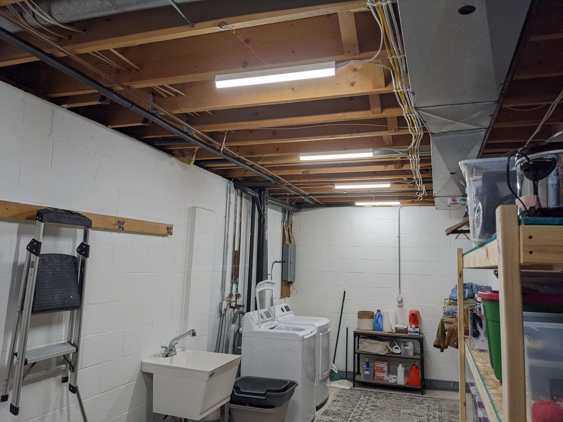 A laundry room with a washer and dryer , sink , and ladder.