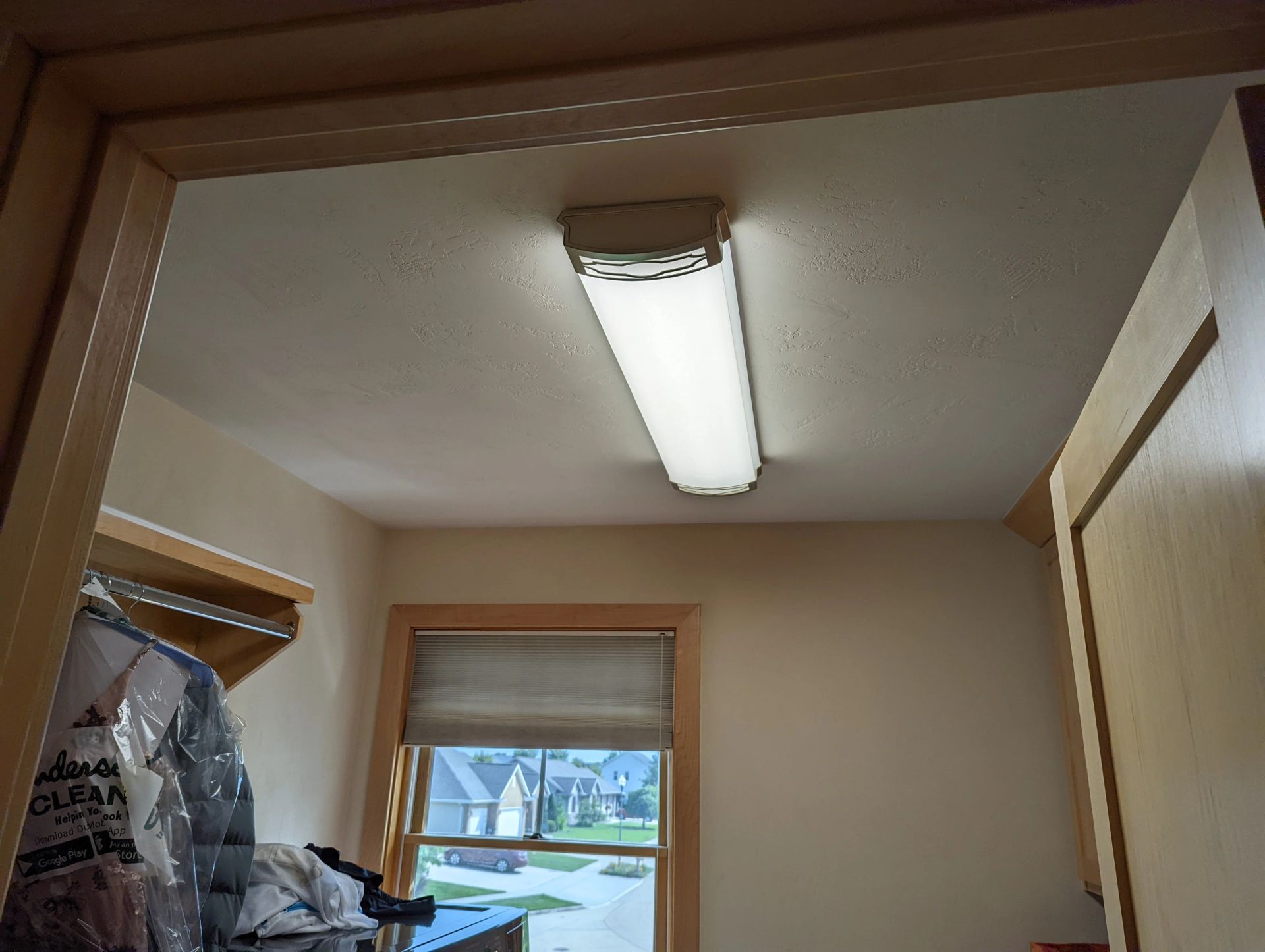 A laundry room with a light on the ceiling and a window.