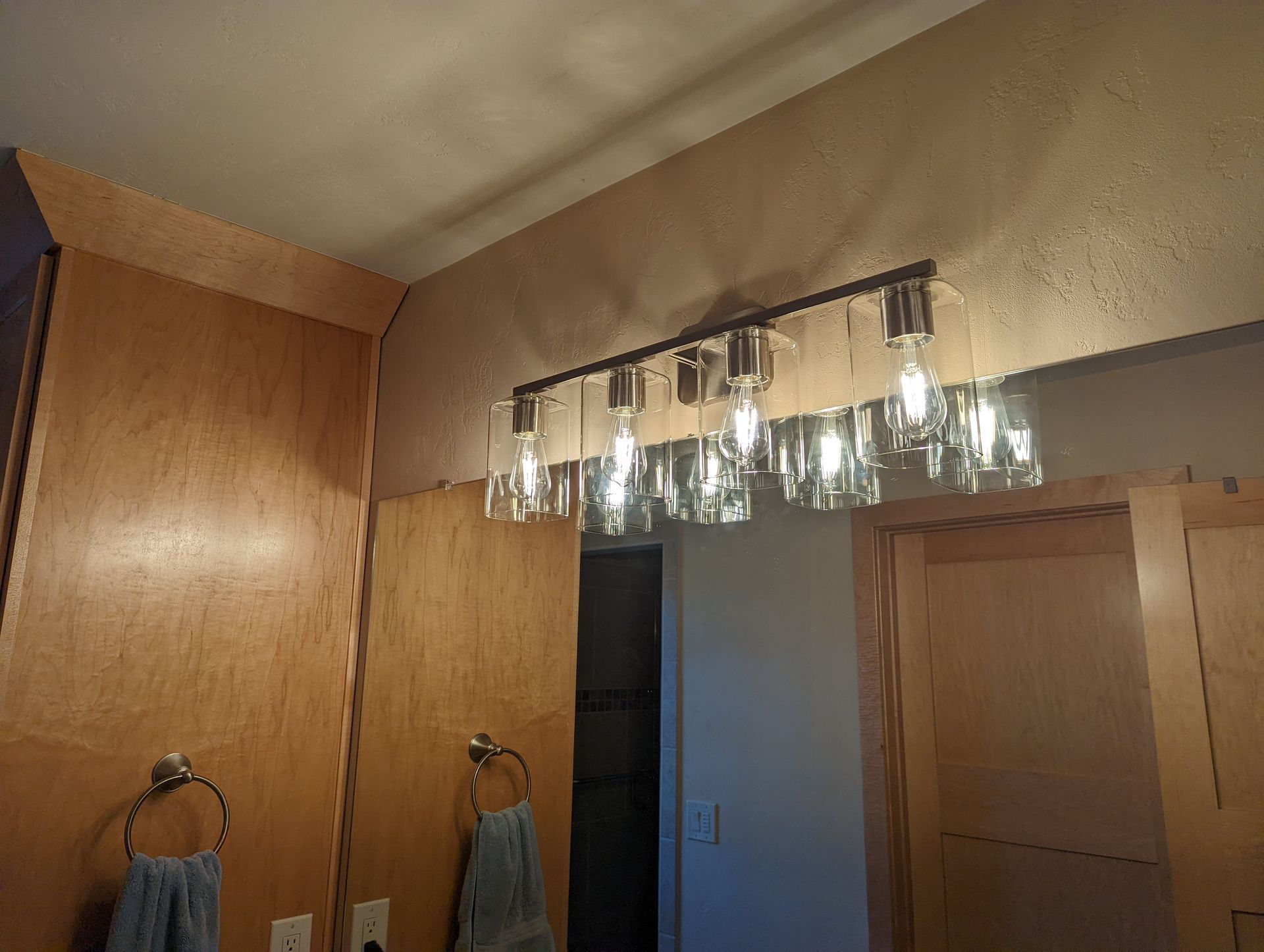 A bathroom with a mirror and a light fixture hanging from the ceiling.