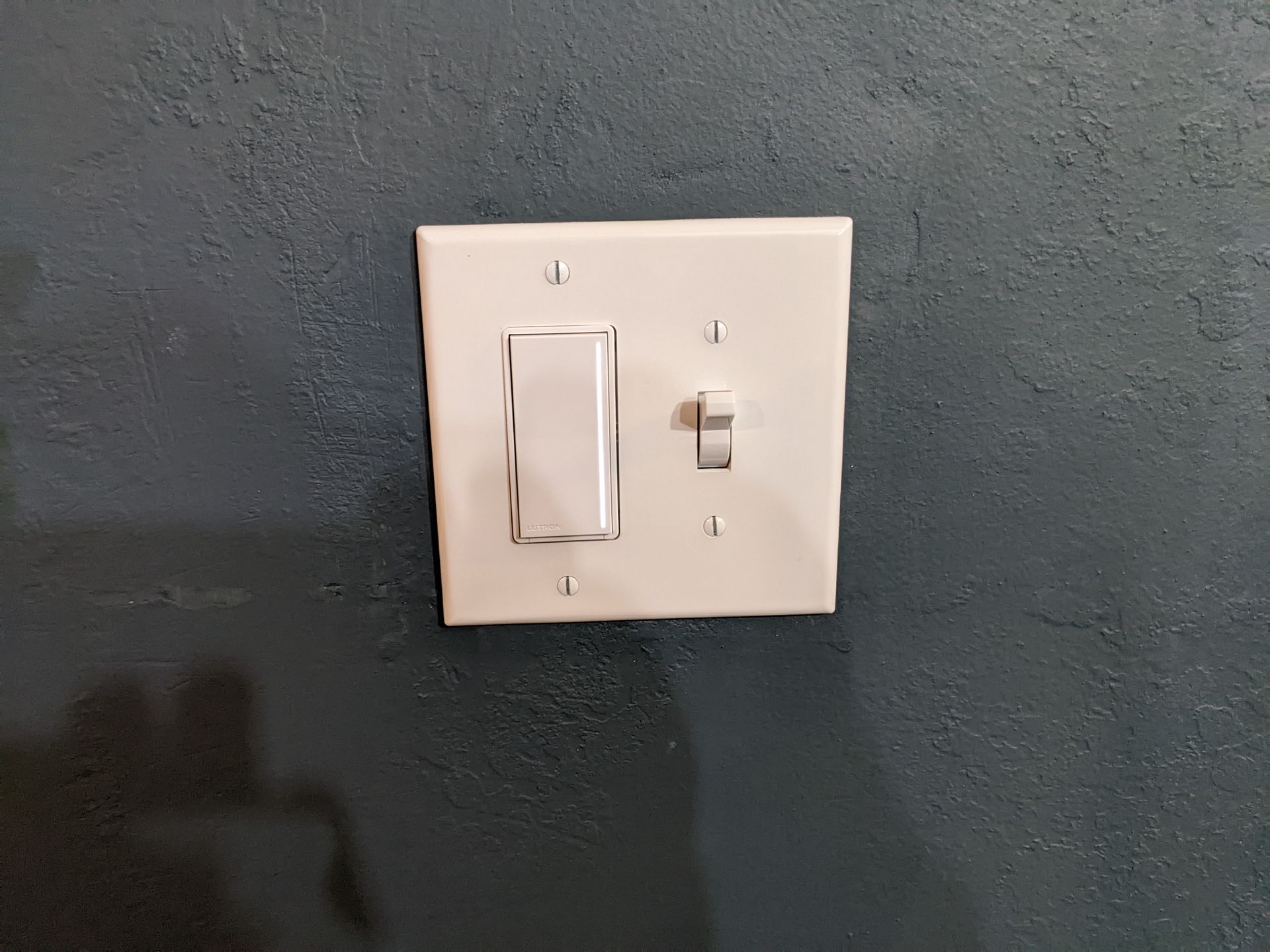 A white light switch is mounted on a blue wall.