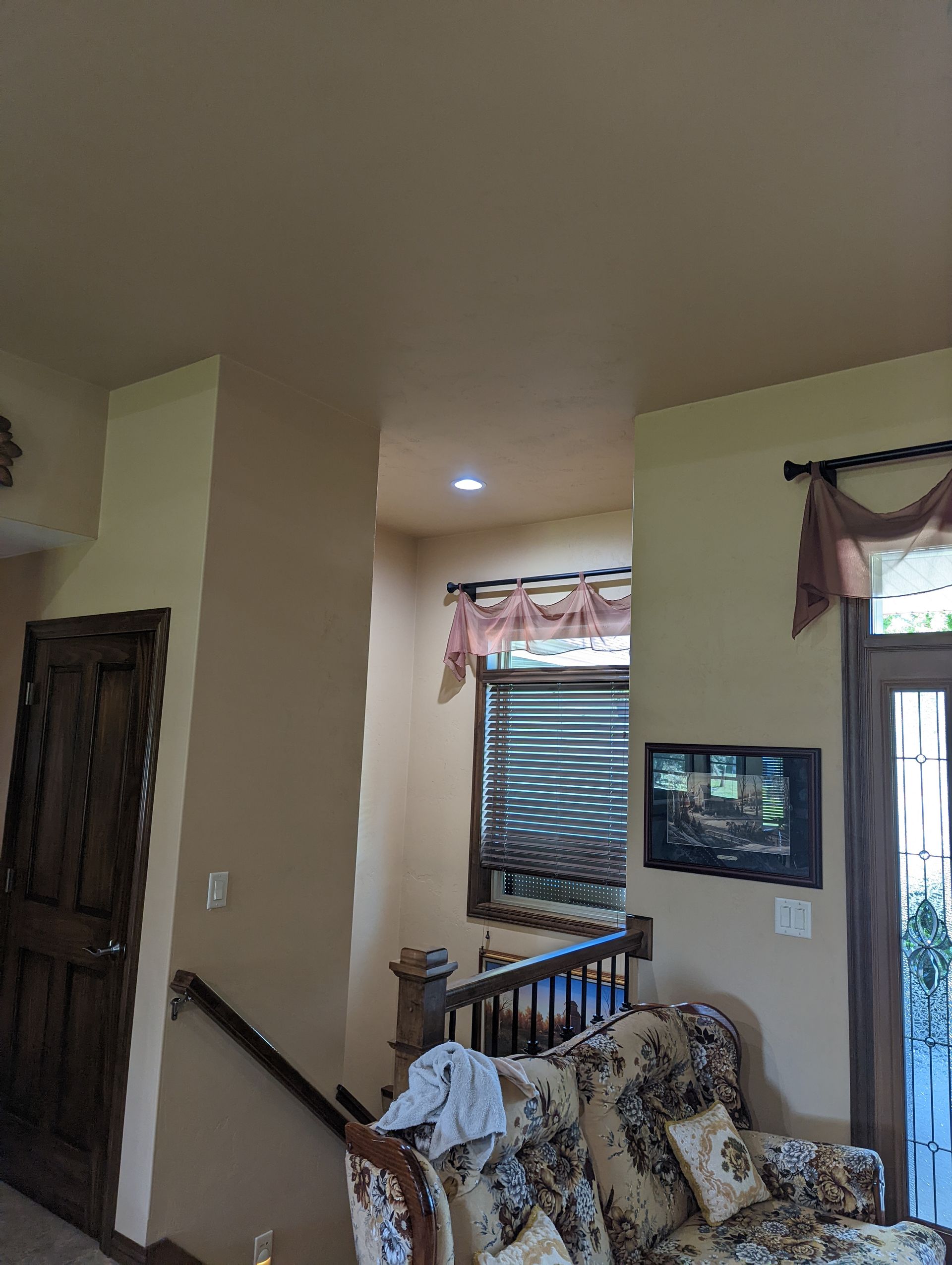A living room with a couch , chair , television and stairs.