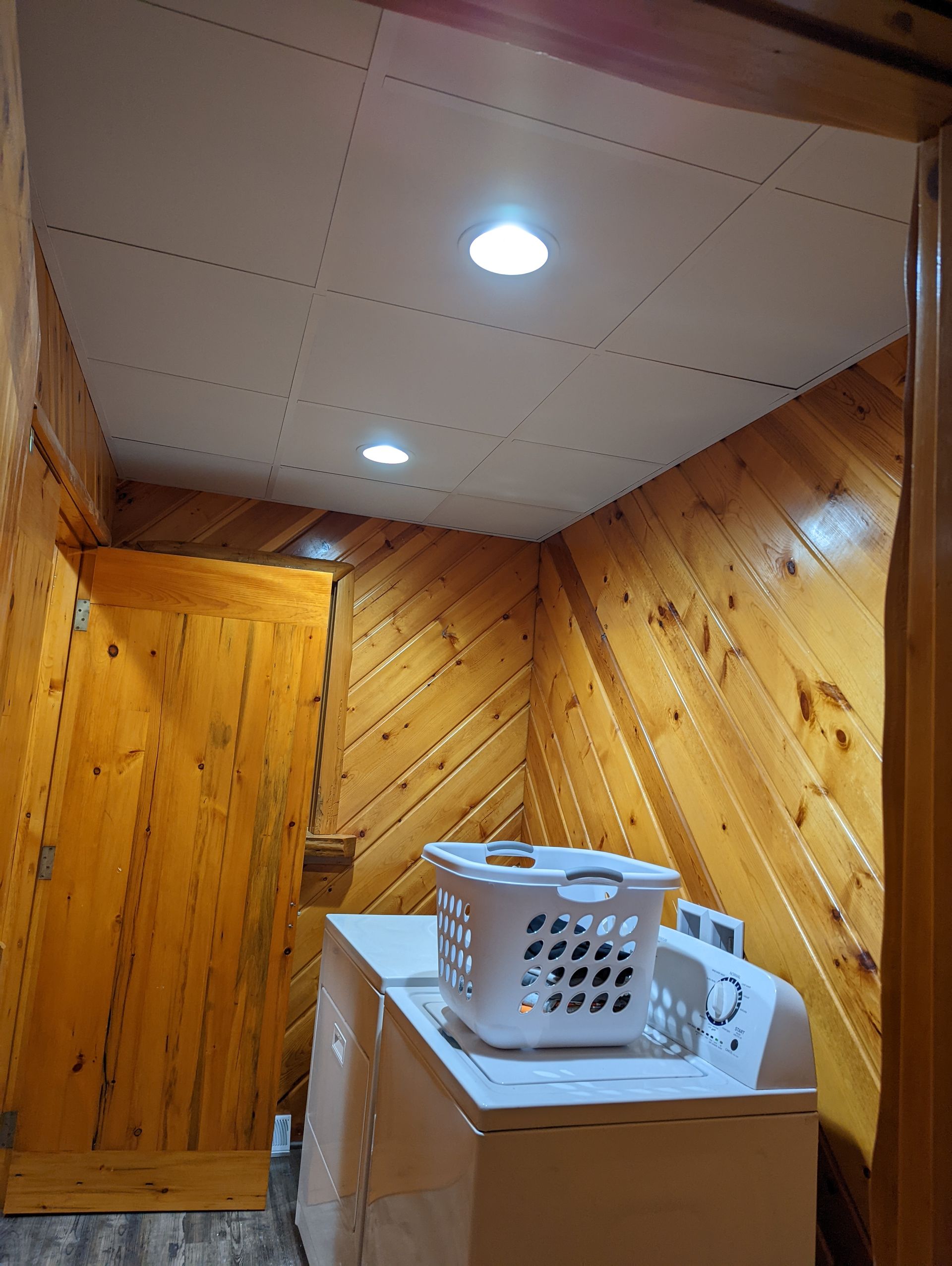 A laundry room with a washer and dryer and a basket on top of it.