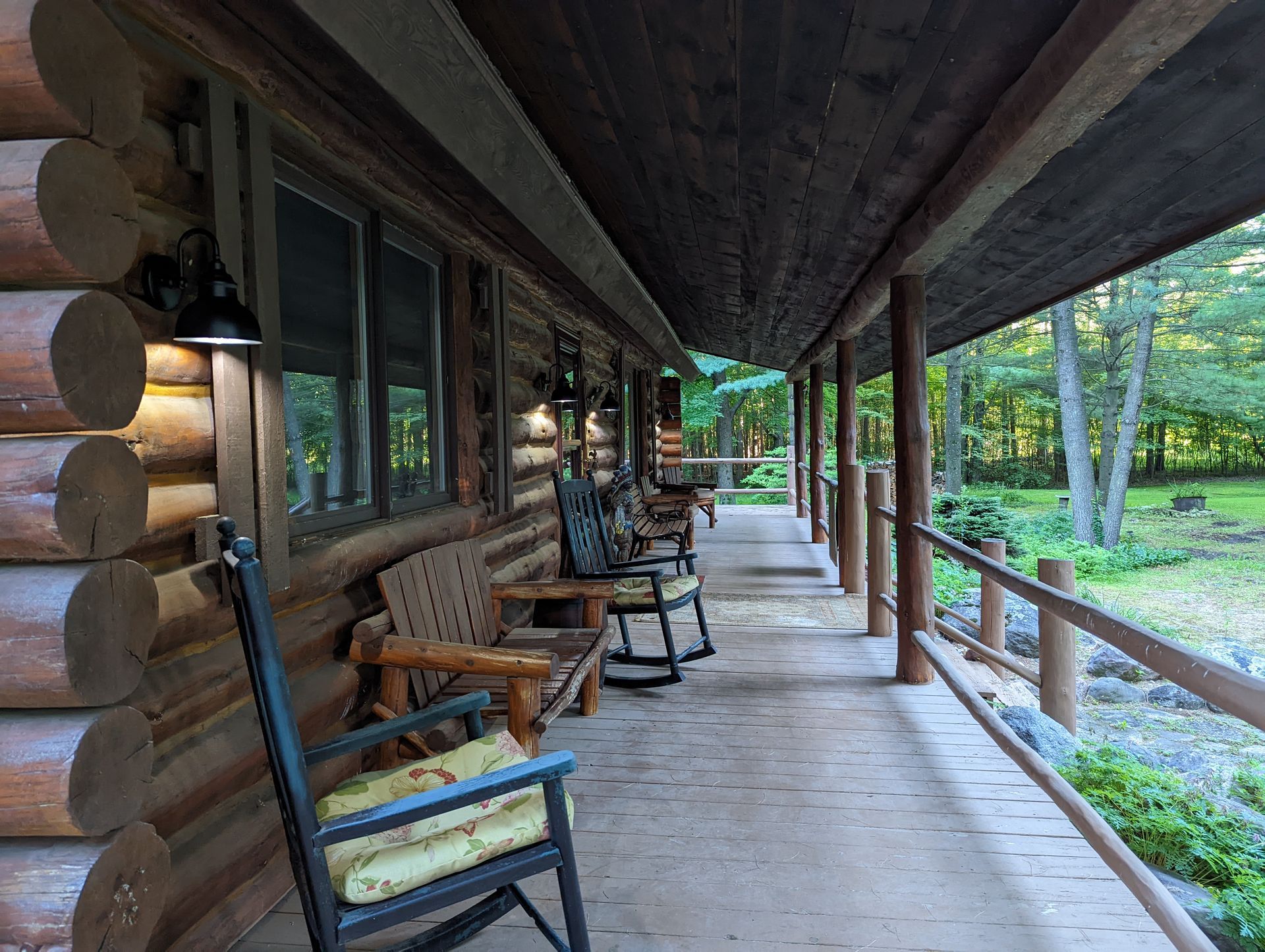 There are rocking chairs on the porch of a log cabin.