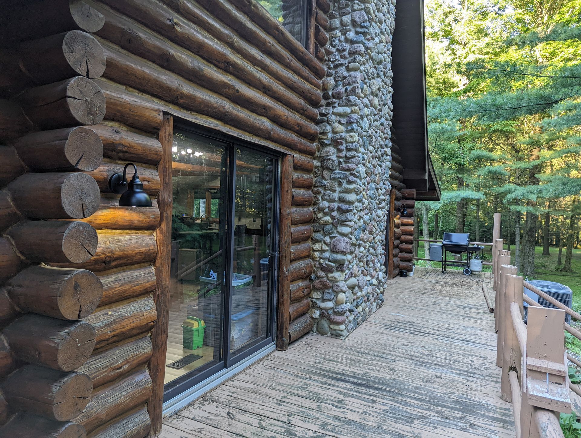 A log cabin with a large stone fireplace and sliding glass doors.