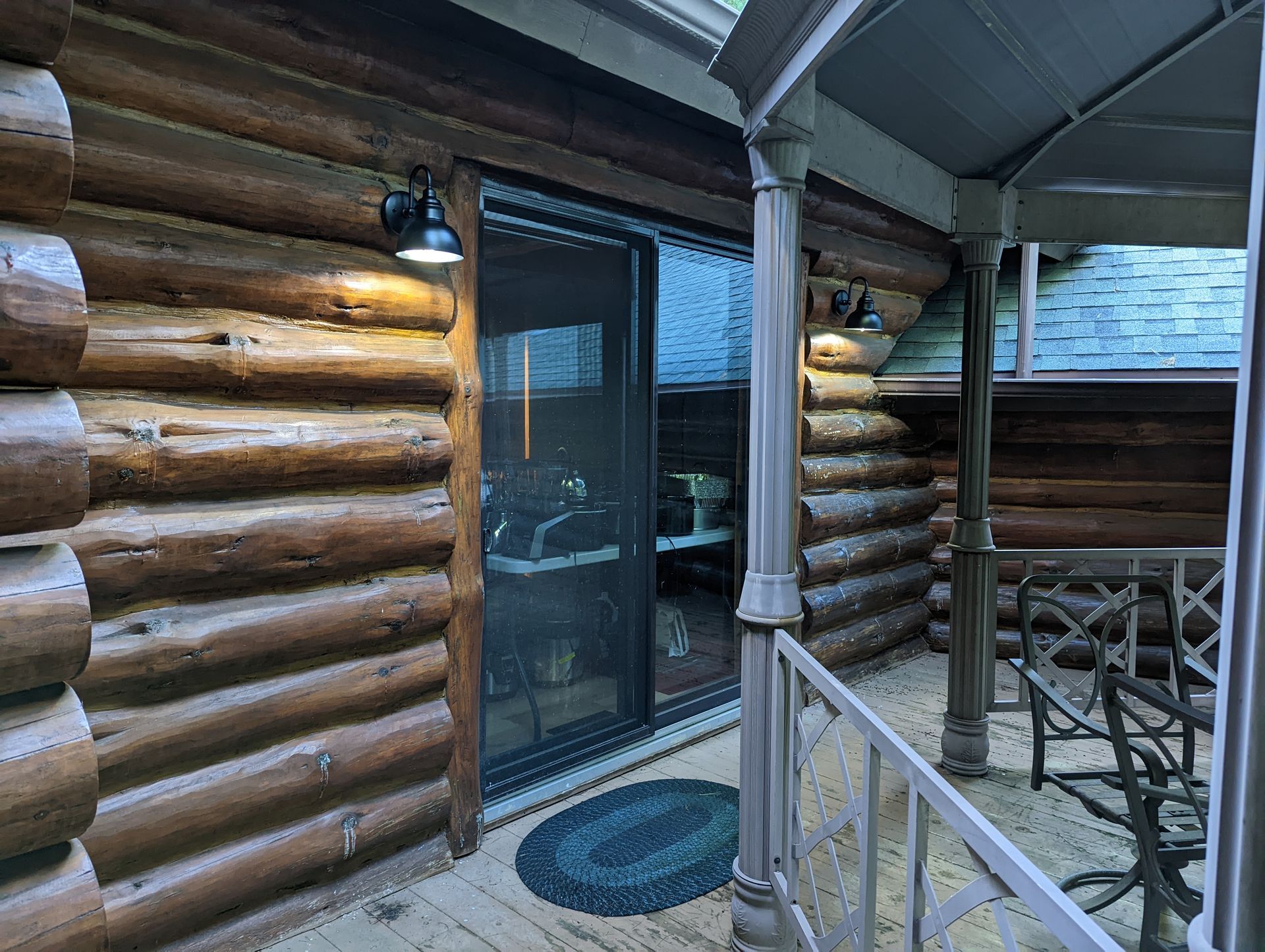 A log cabin with a sliding glass door and a porch.