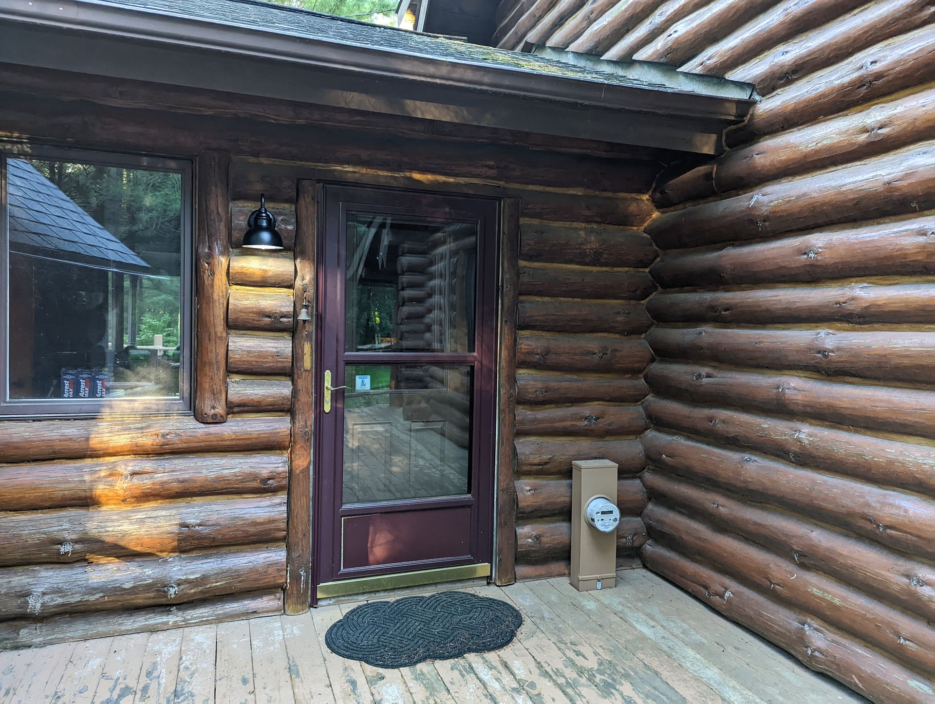 The front door of a log cabin with a glass door.