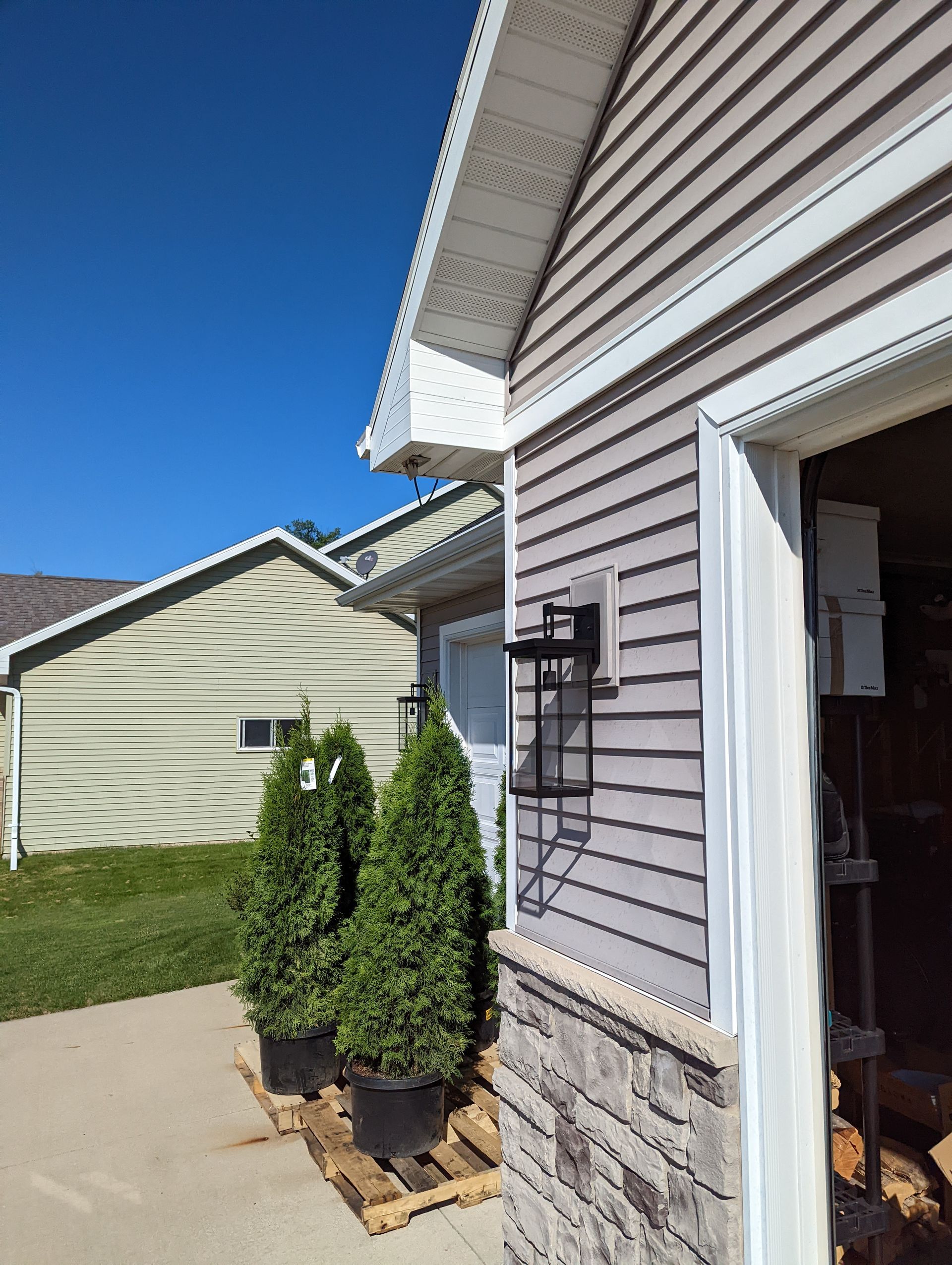 A house with a garage and potted trees in front of it.