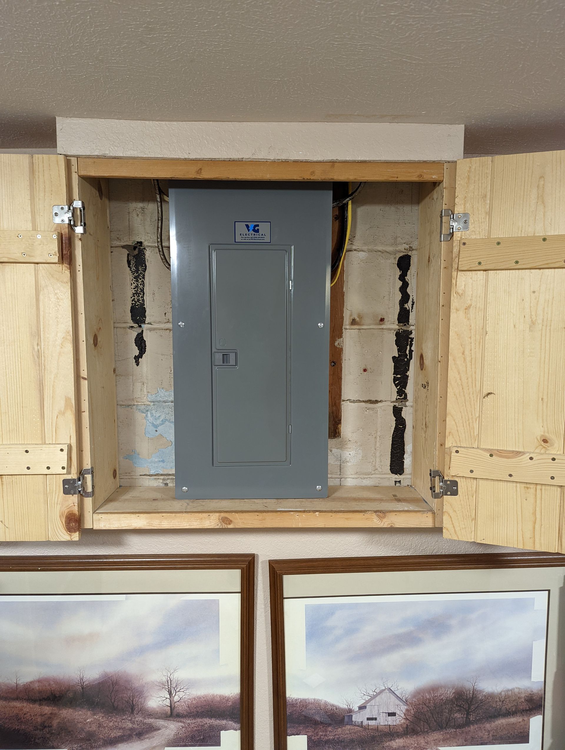 A picture of a farm is hanging on a wall next to a electrical box