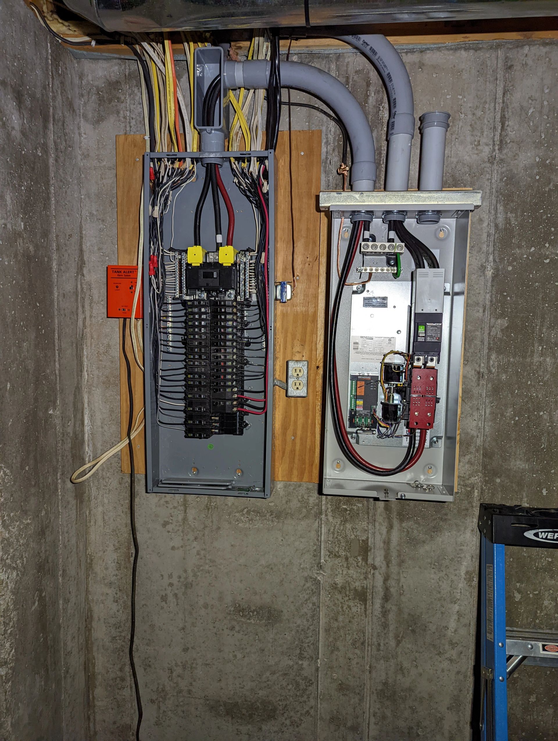 An electrical box is hanging on a wall next to a ladder