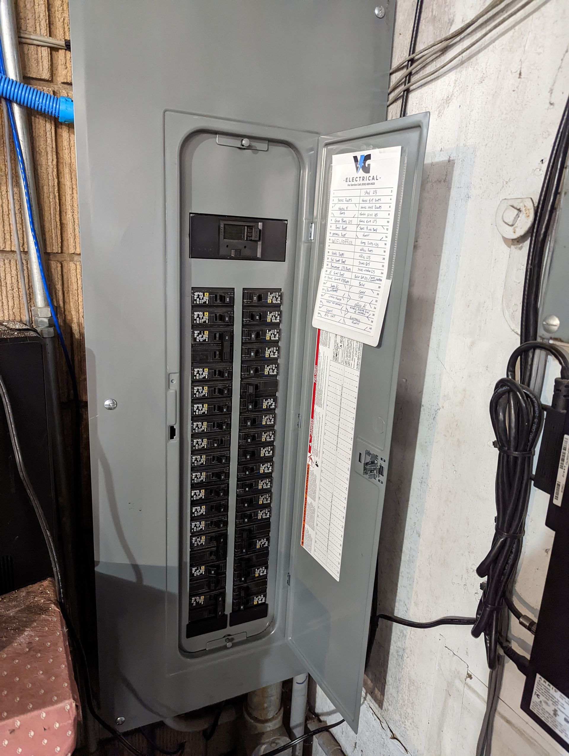 A electrical box with the door open is sitting on a wall.