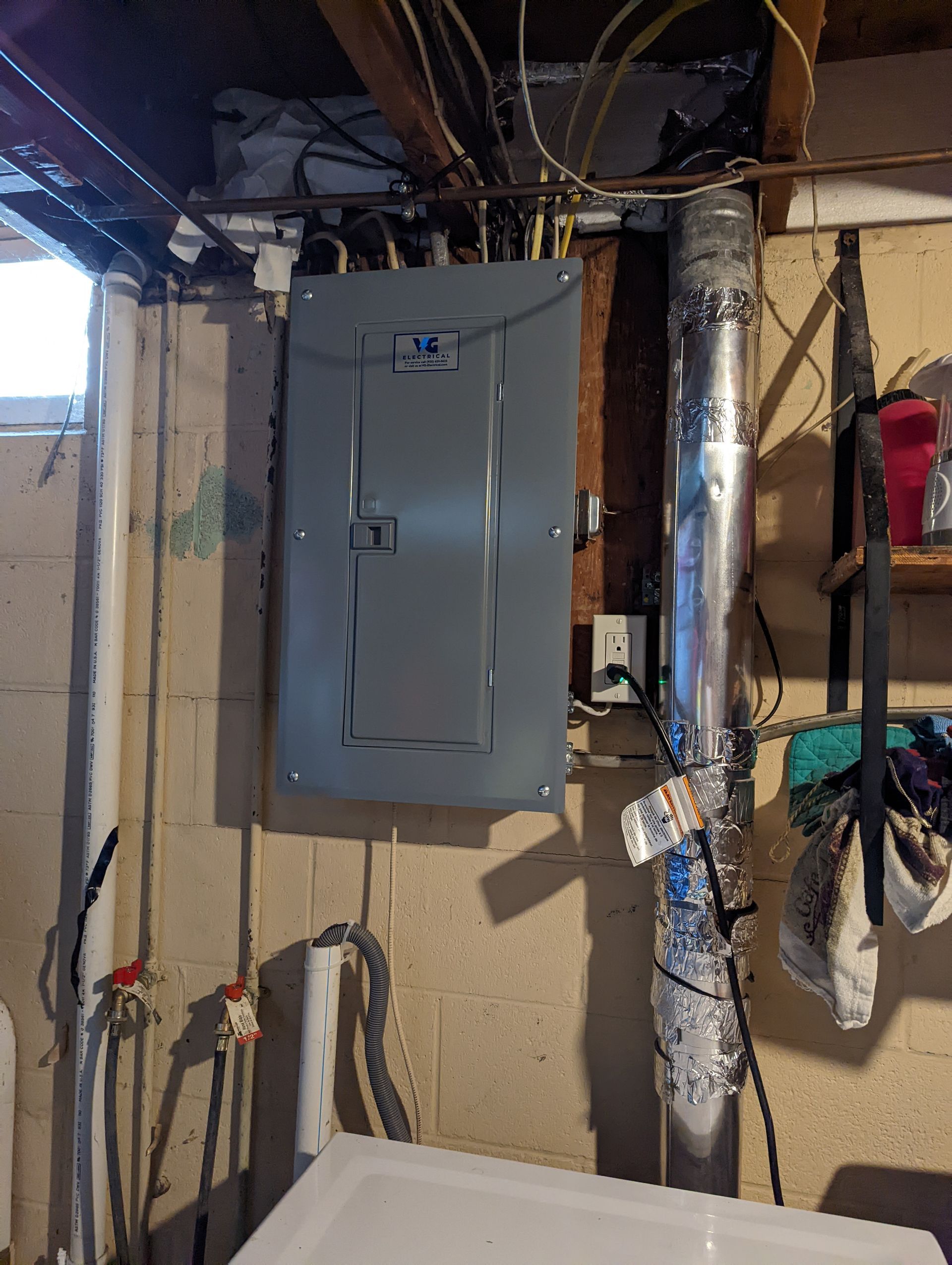 A utility box is hanging on the wall in a laundry room.
