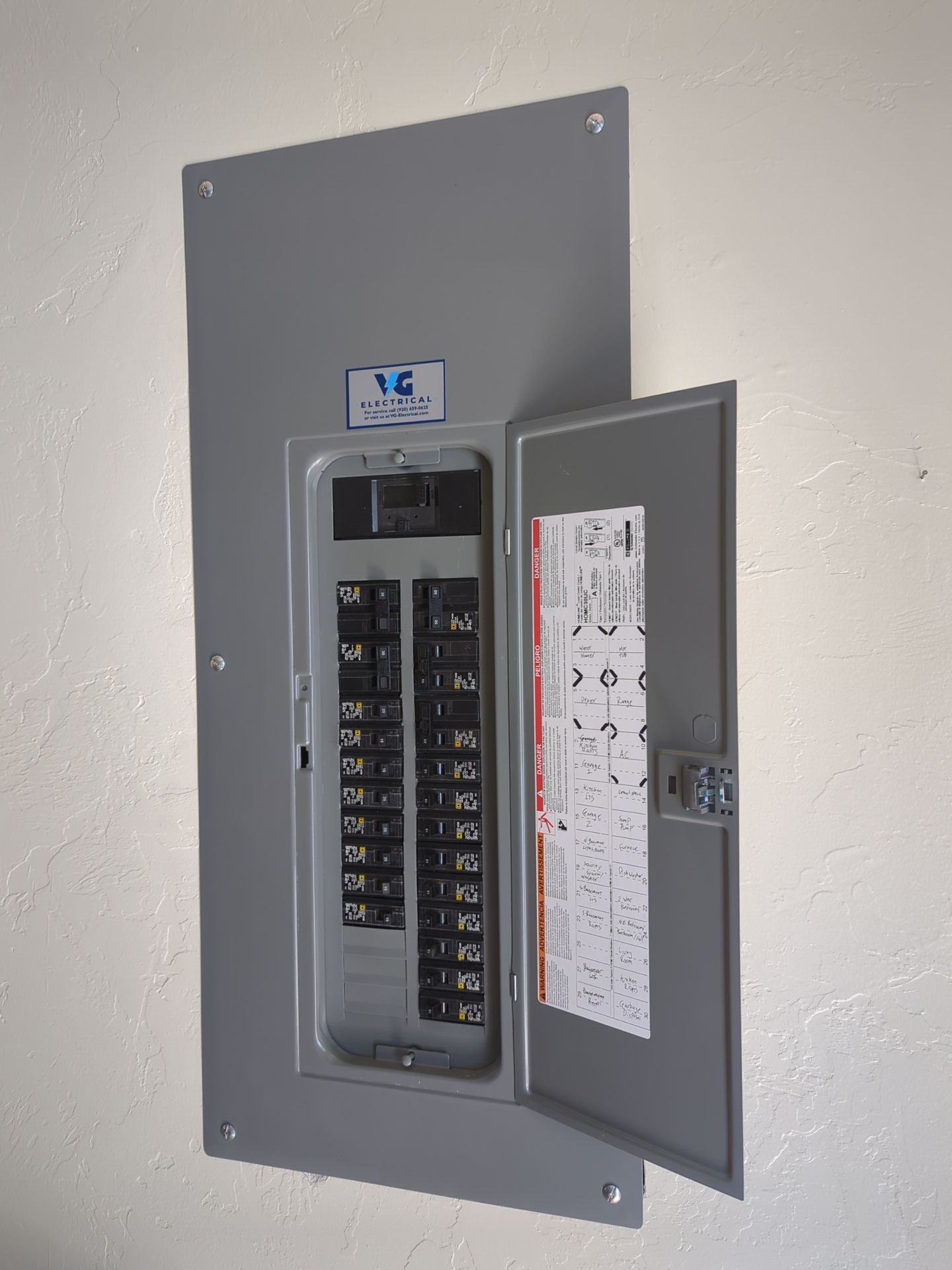 A gray electrical box with the door open on a white wall