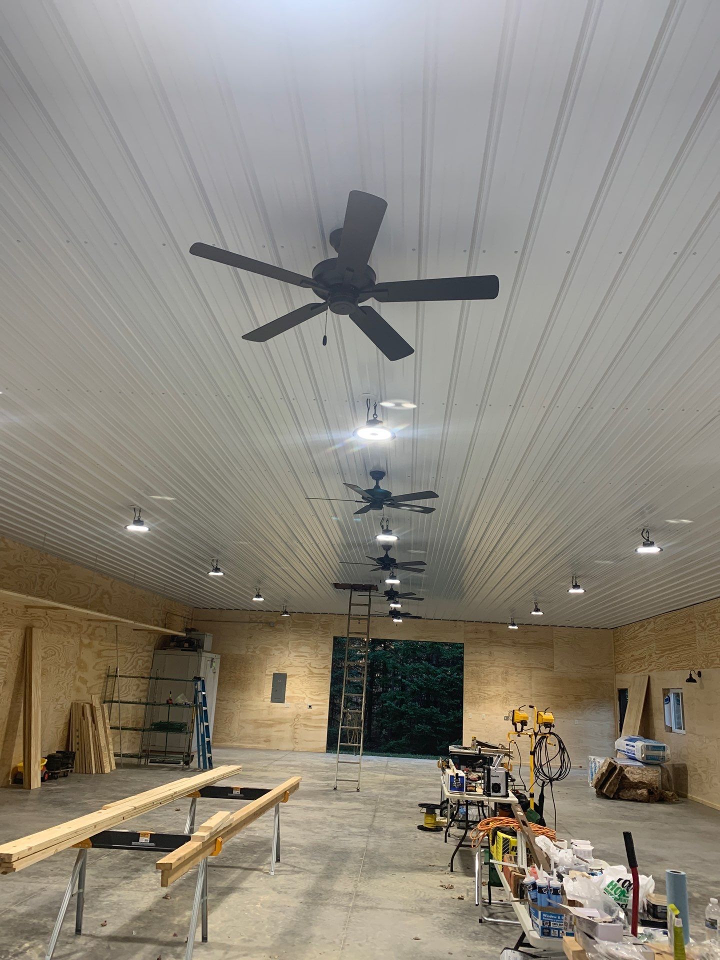A ceiling fan is hanging from the ceiling of a building under construction.