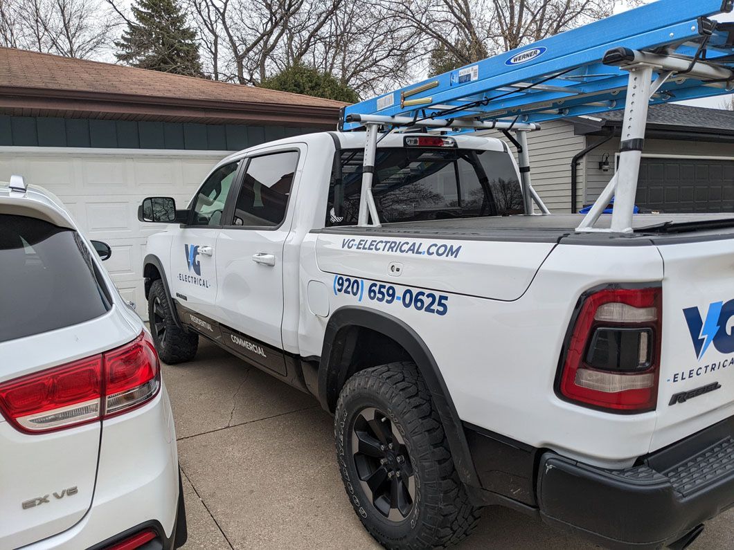 A white truck is parked in front of a garage next to a white suv.