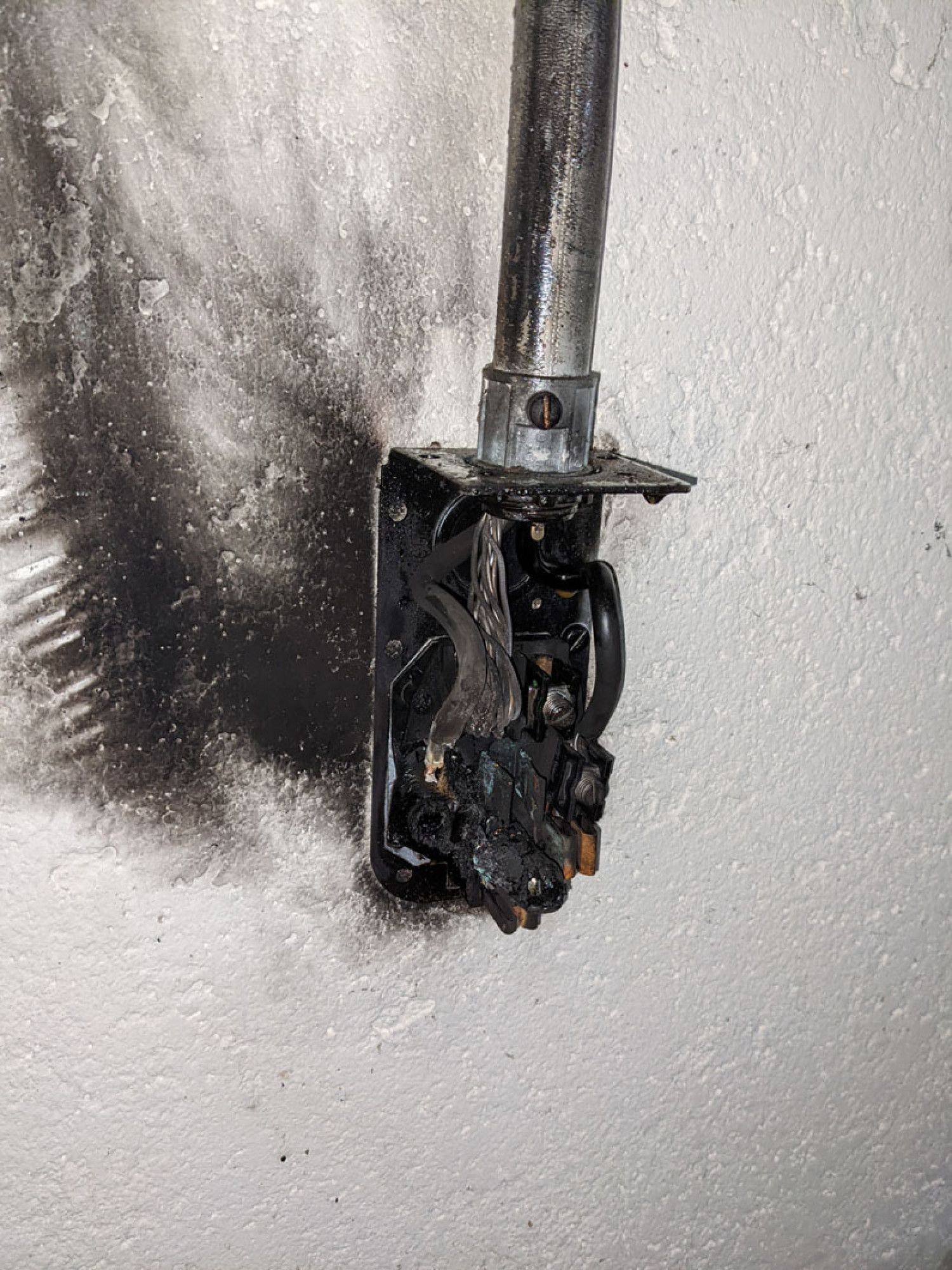 A close up of a metal object on a white wall.