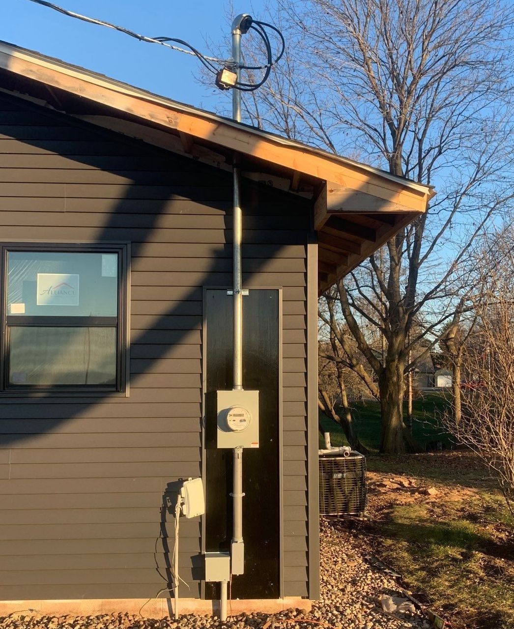 A black house with a telephone pole on the side of it.